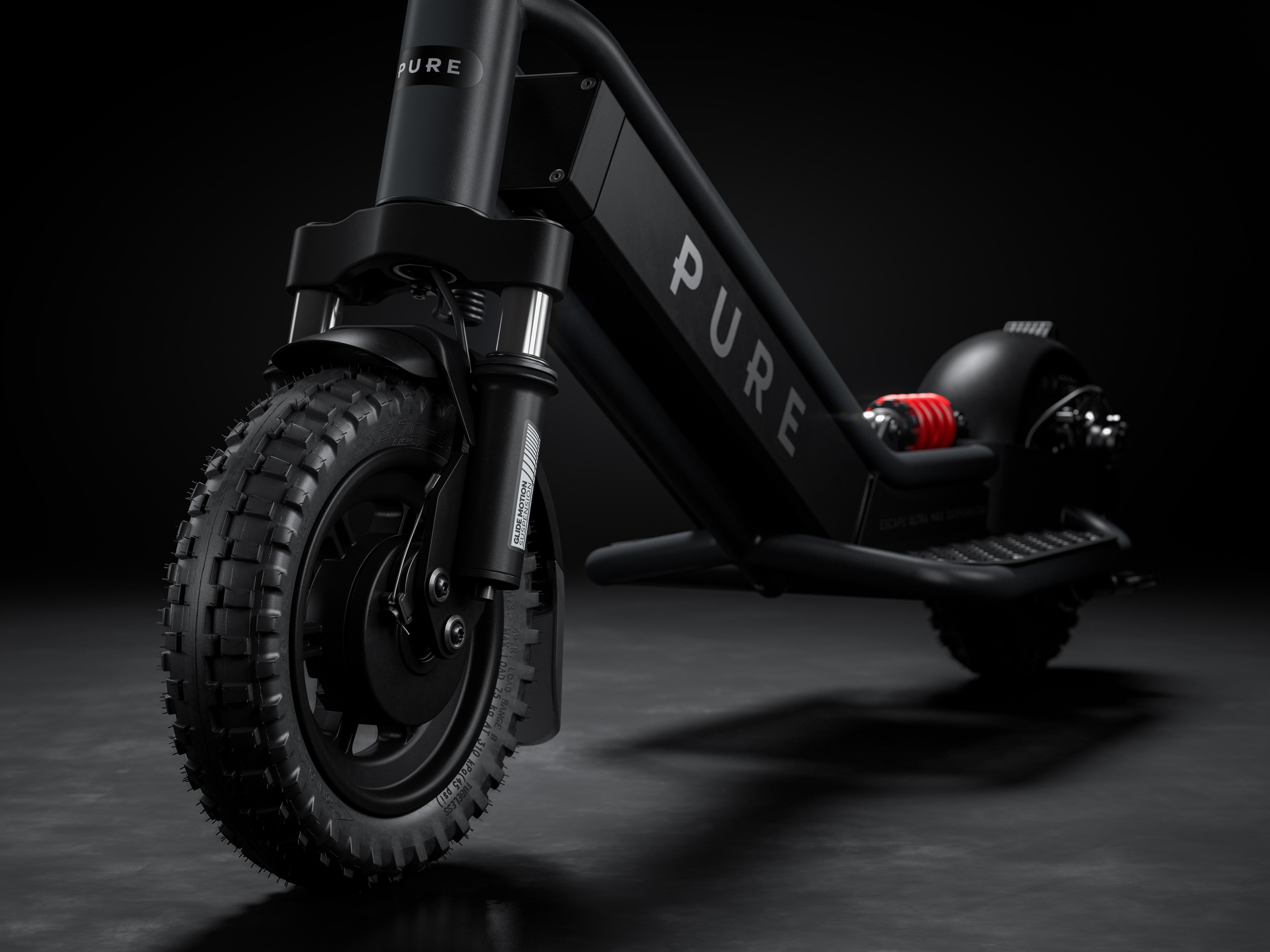 Schwarzer E-Scooter mit grobstolligem Reifen und Federung, auf dunklem Untergrund.