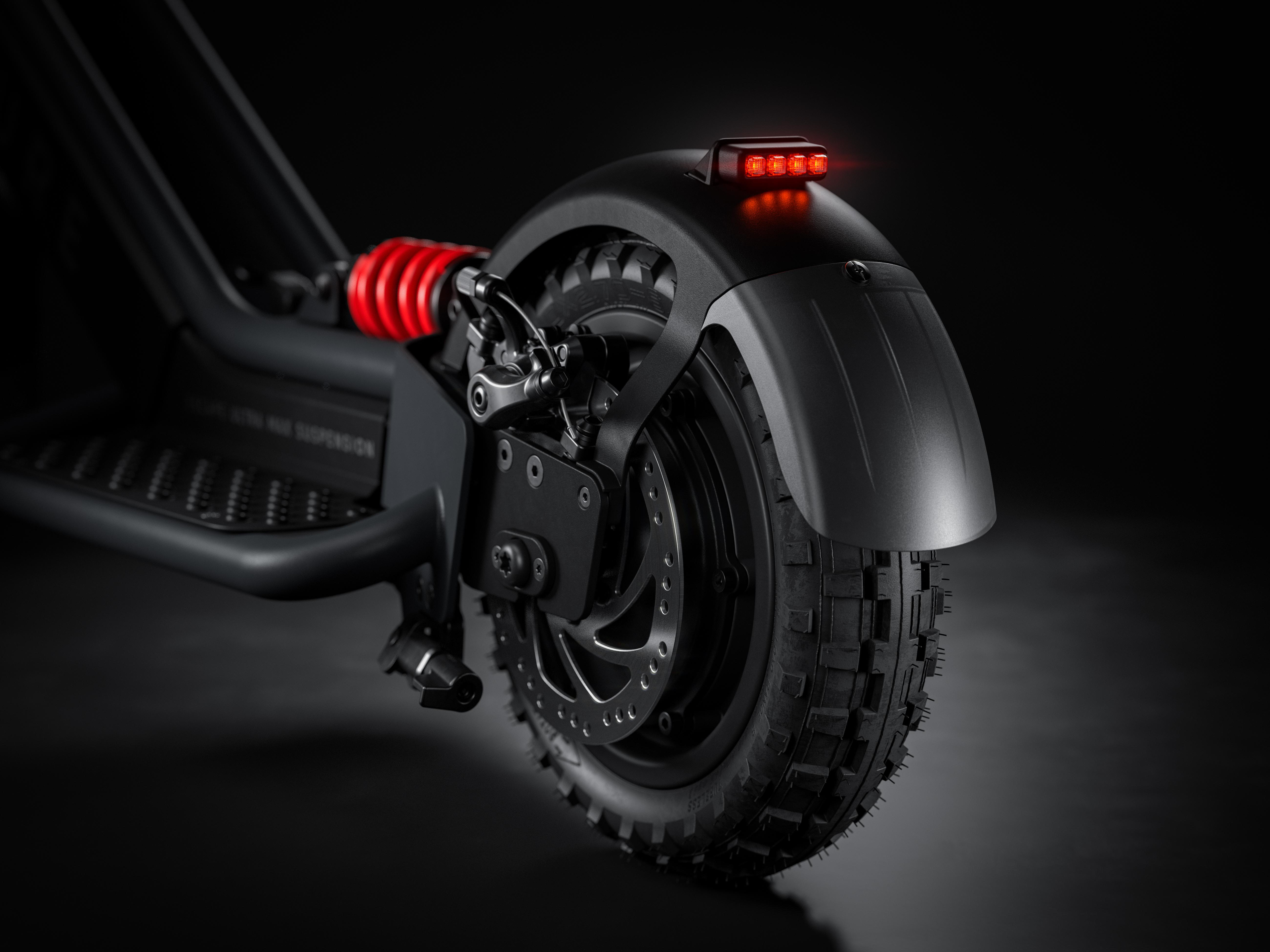 Detailaufnahme eines schwarzen E-Scooters mit roter Federung und Reifen.