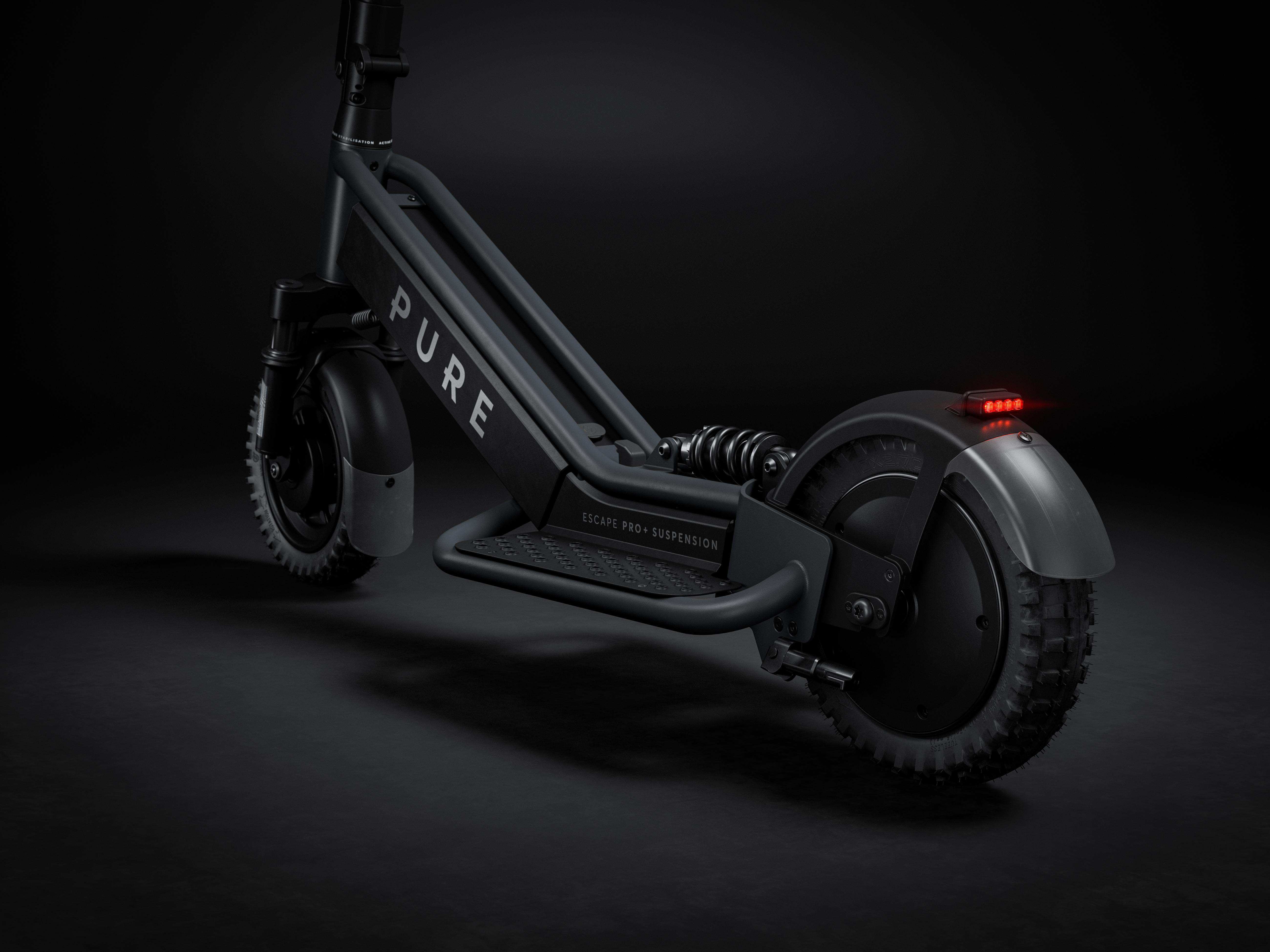 Ein schwarzer E-Scooter mit Federung und roten Rücklichtern auf dunklem Grund.