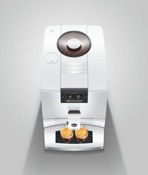Eine weiße Kaffeemaschine mit zwei Espressotassen und Bohnenbehälter oben.