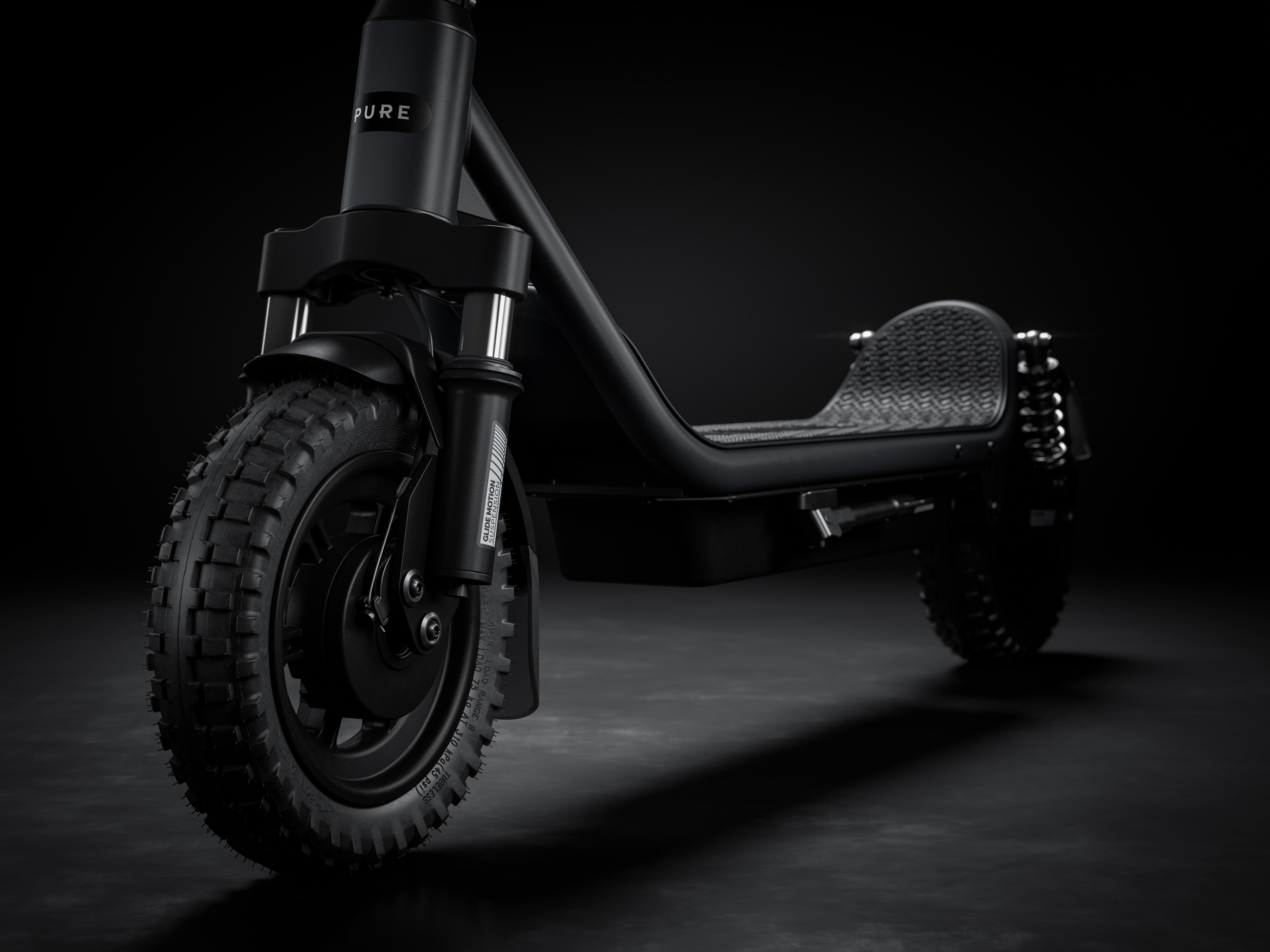 Ein schwarzer E-Scooter mit breiten Reifen und Federung vor dunklem Hintergrund.