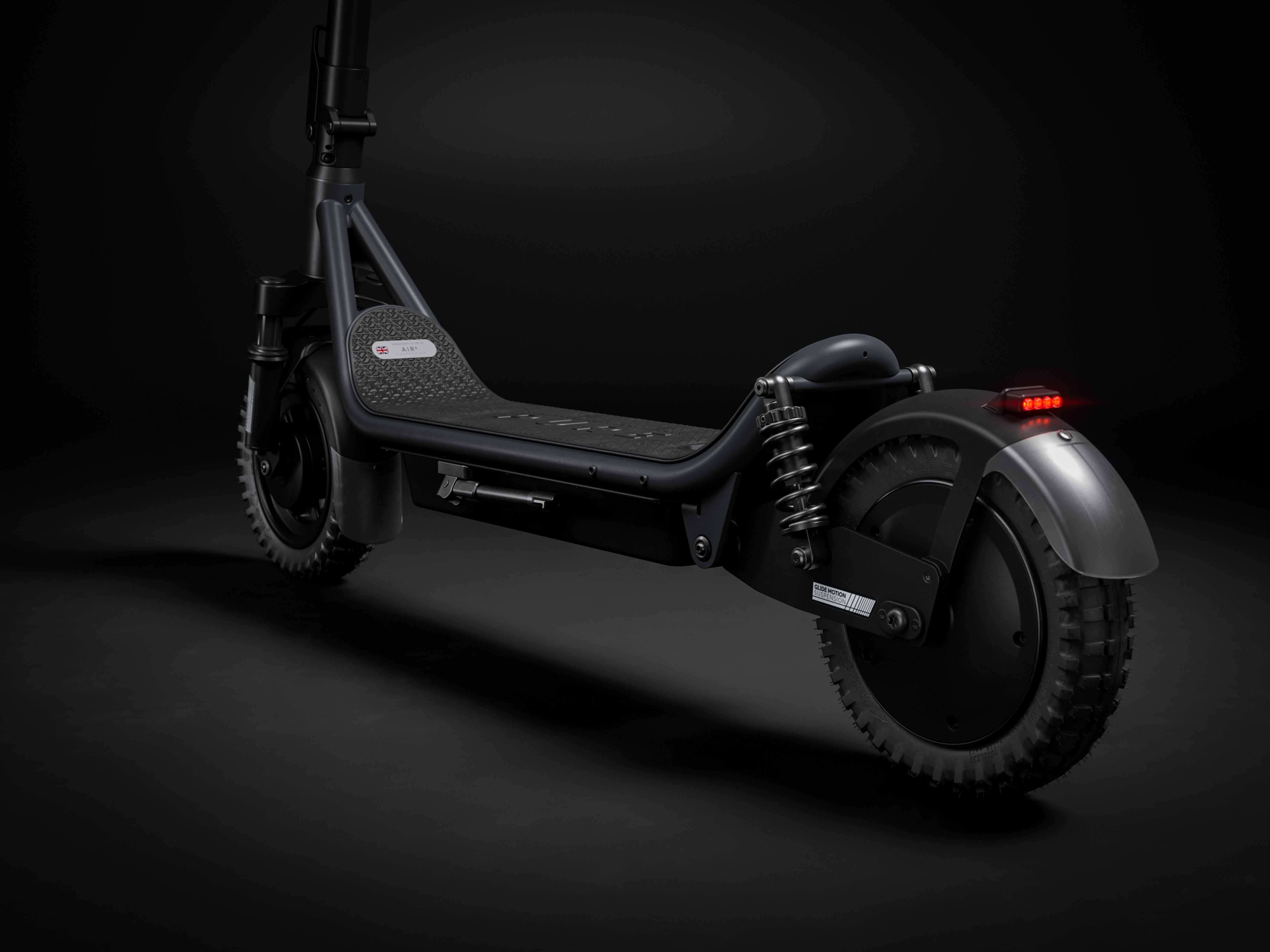 Ein schwarzer E-Scooter mit gefedertem Heck und roten Rücklichtern.