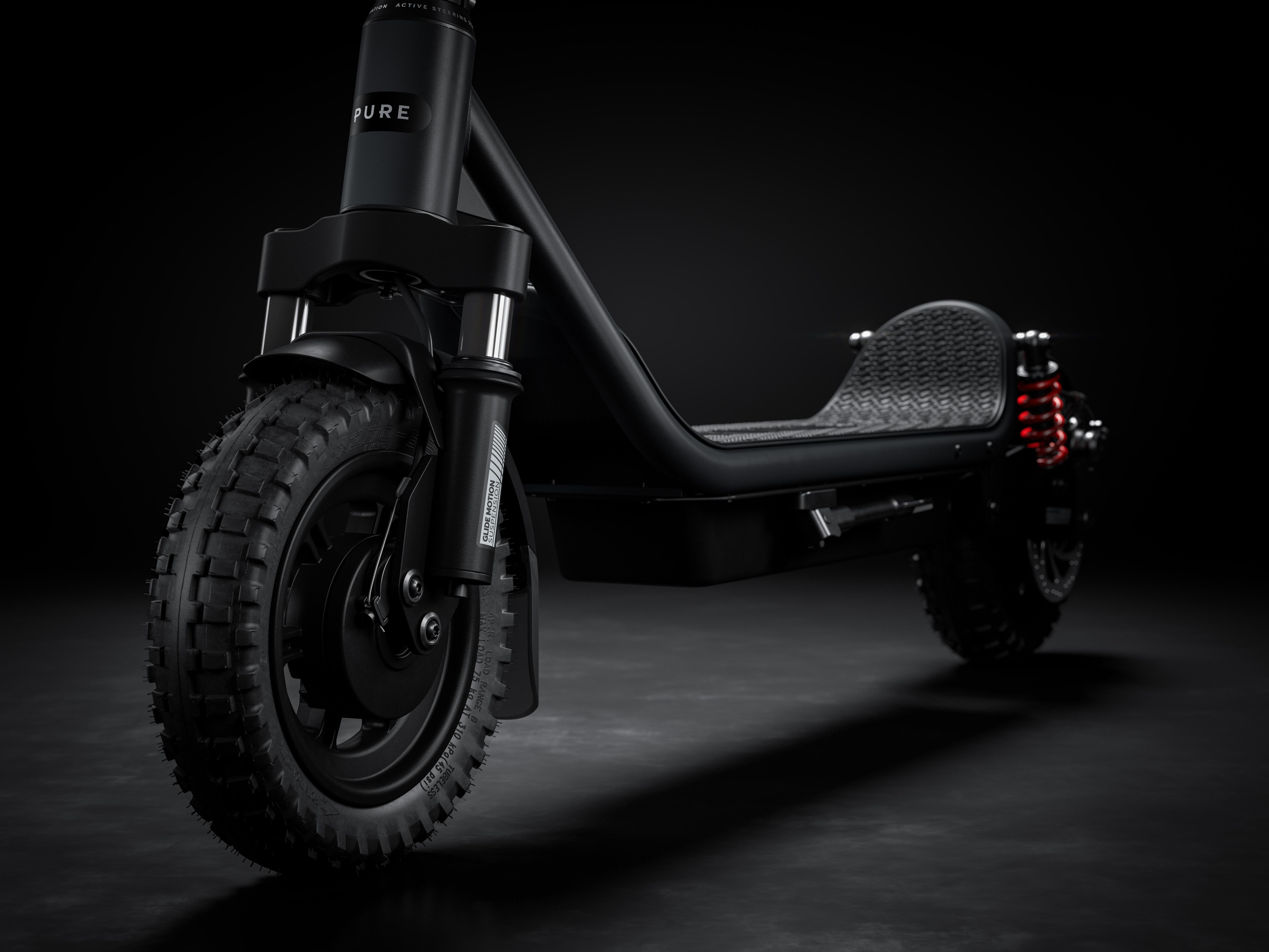 Ein schwarzer E-Scooter mit grobstolligen Reifen und roten Stoßdämpfern.