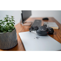 Ein Laptop mit Kopfhörern, Tastatur, Maus und Pflanze auf einem Holztisch.