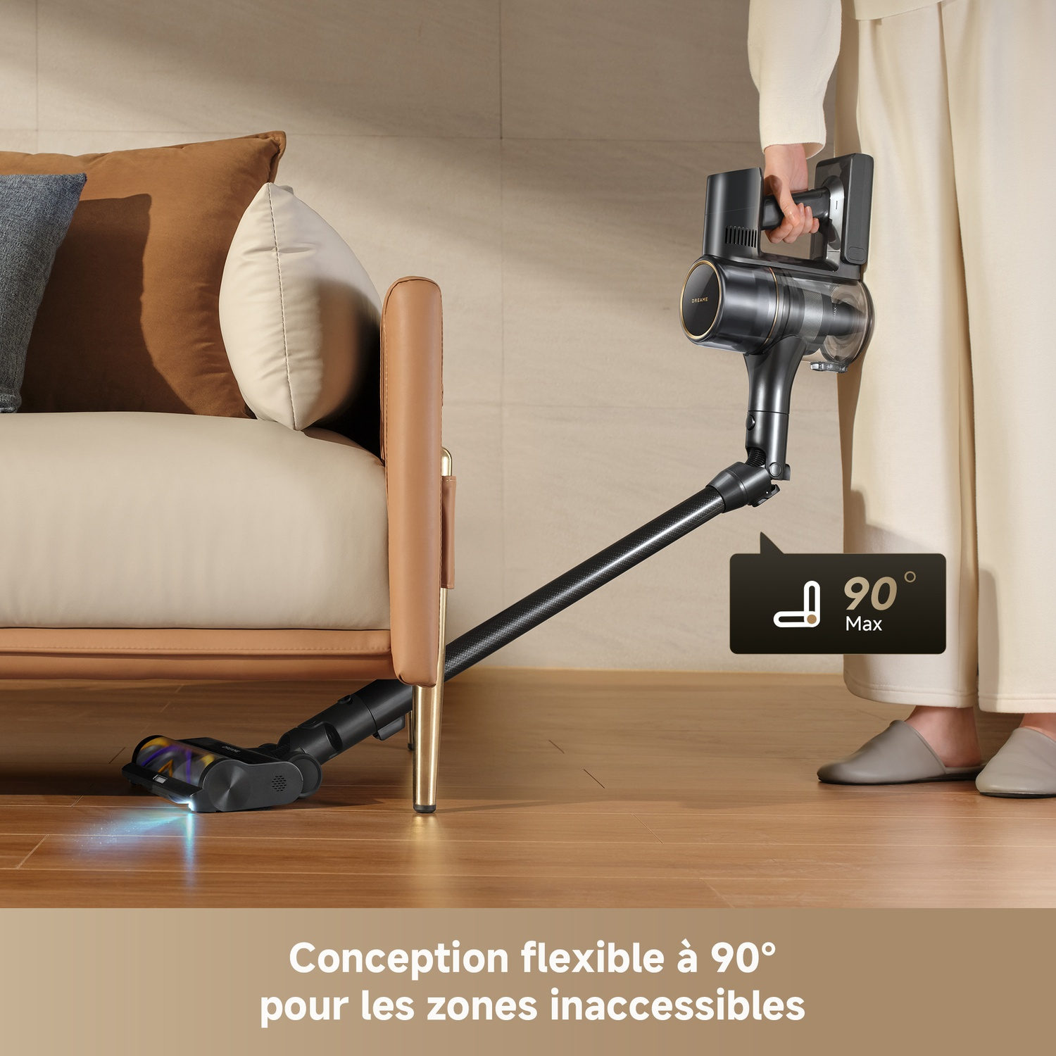 Un aspirateur noir à main est utilisé pour aspirer sous un canapé.