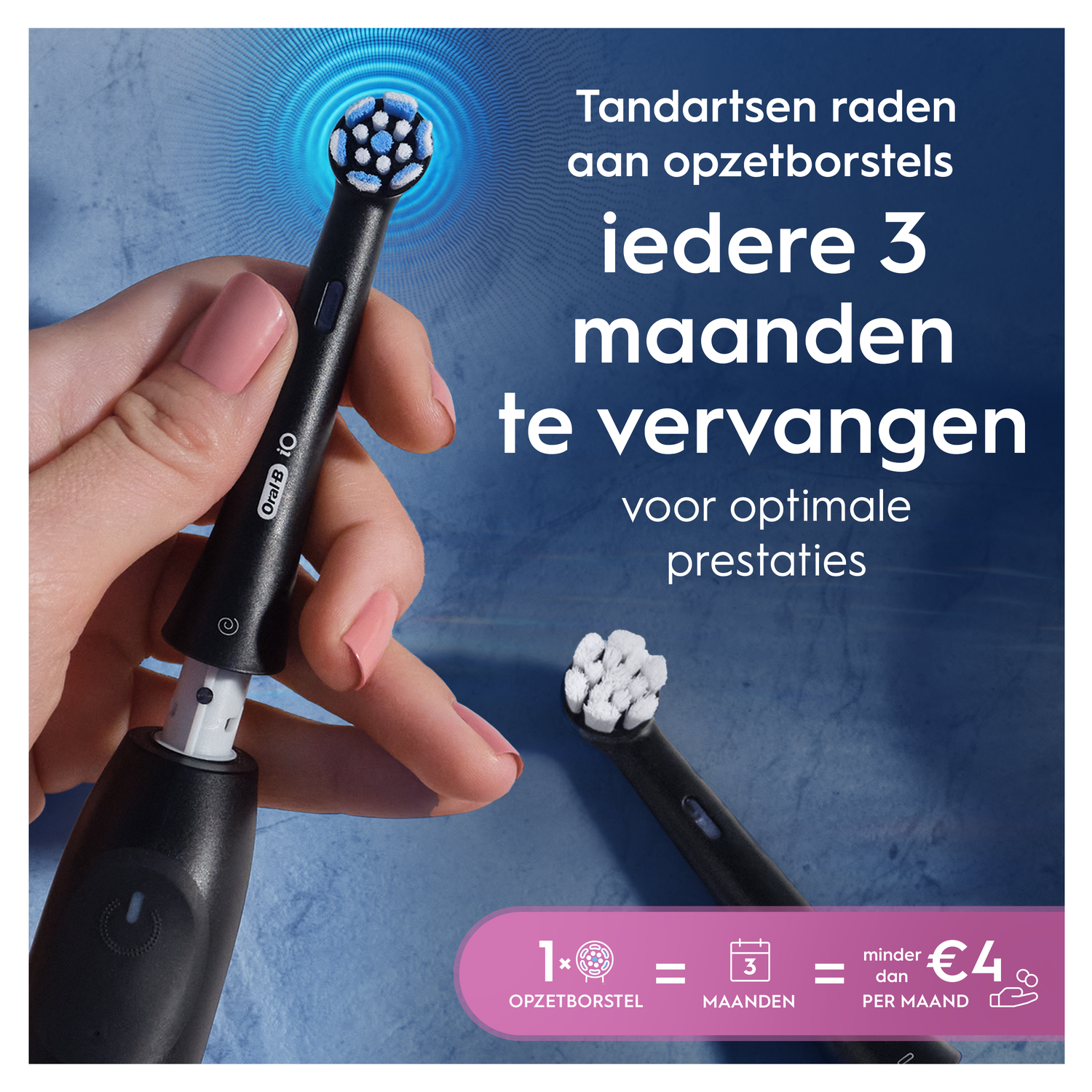 A hand holds an electric toothbrush, showing a brush head attachment.
