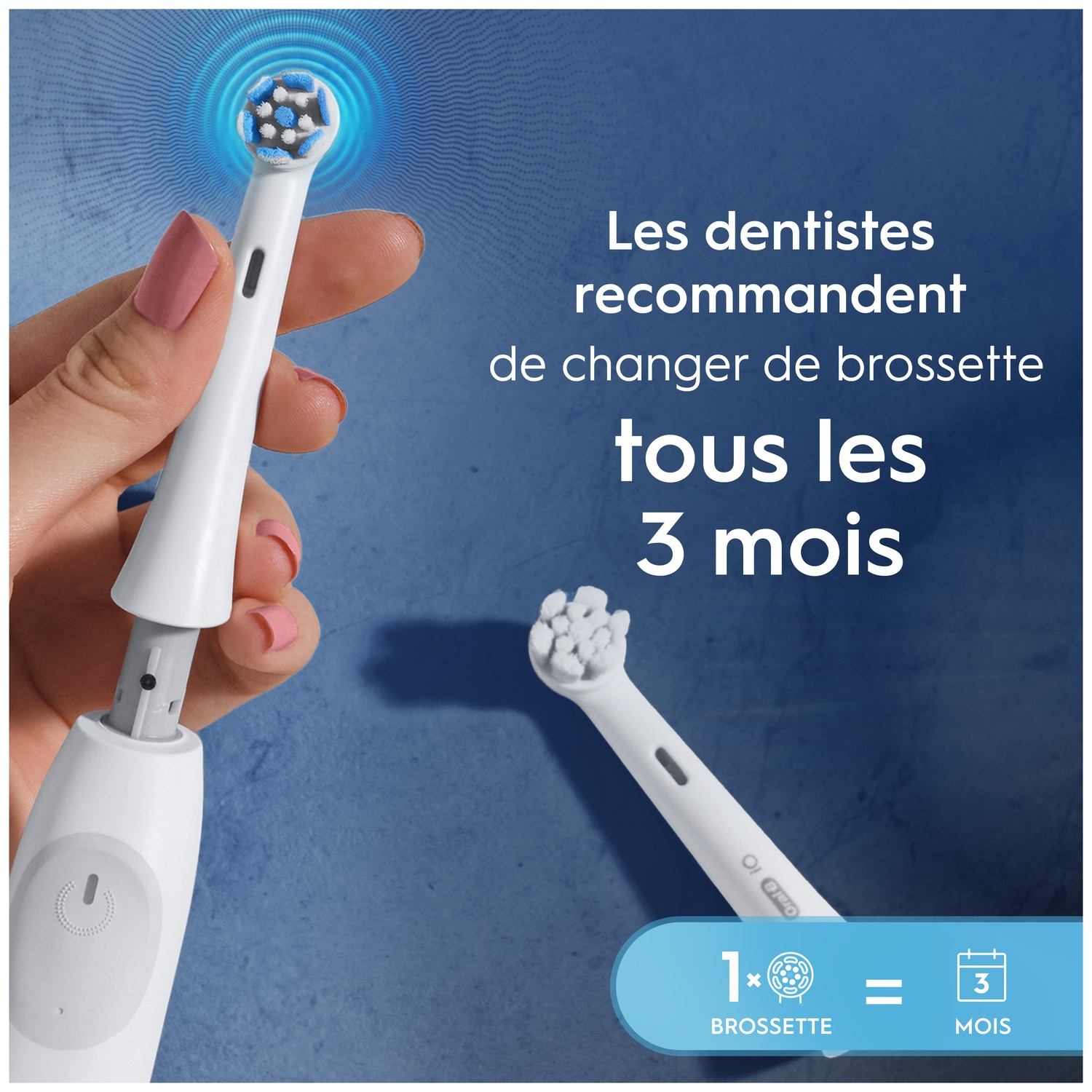 Une main tient une tête de brosse à dents, avec une brosse de rechange à côté.