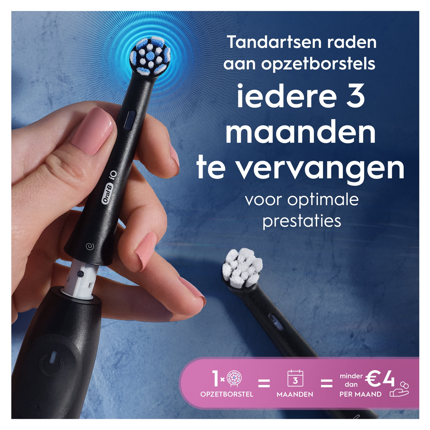 Une brosse à dents électrique noire avec tête est tenue par une main. Une tête est posée à côté.