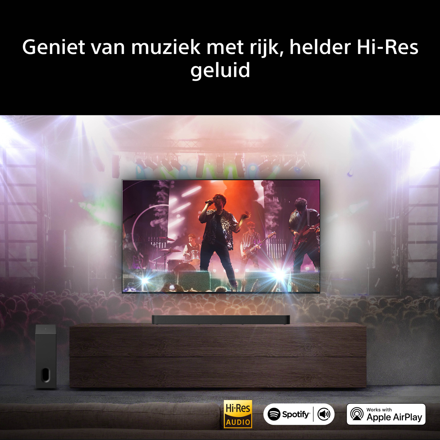 A TV shows a concert with a band and audience. A subwoofer and soundbar are in front.
