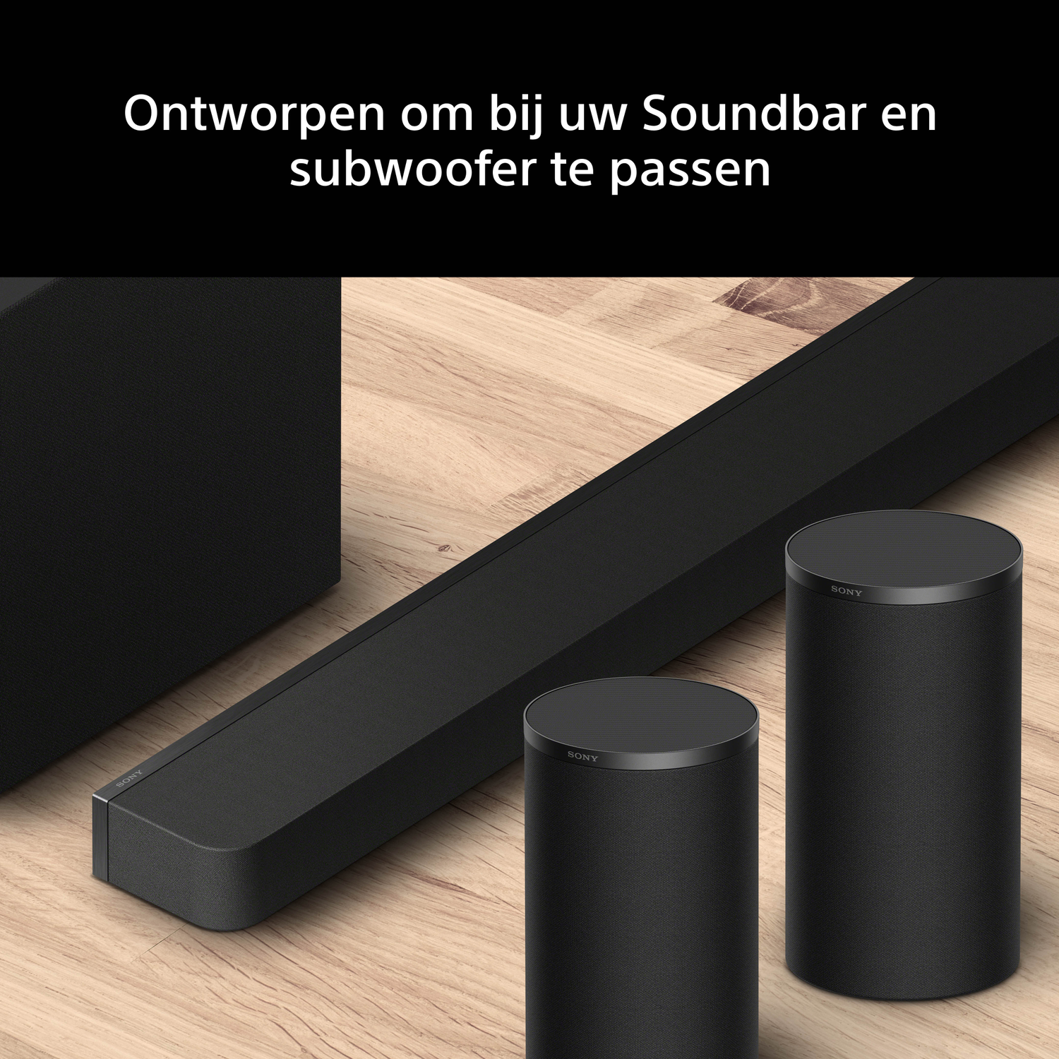 Black Sony soundbar and two cylindrical speakers on a wooden floor.