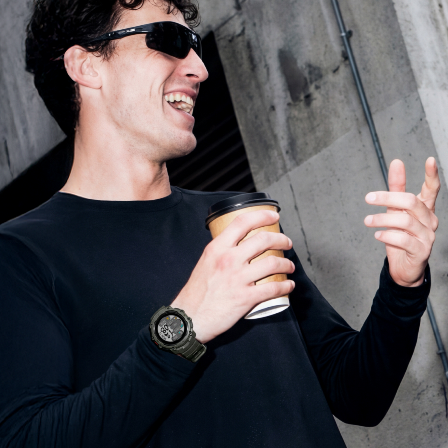 Un hombre con gafas de sol sostiene un vaso de café y lleva un reloj.
