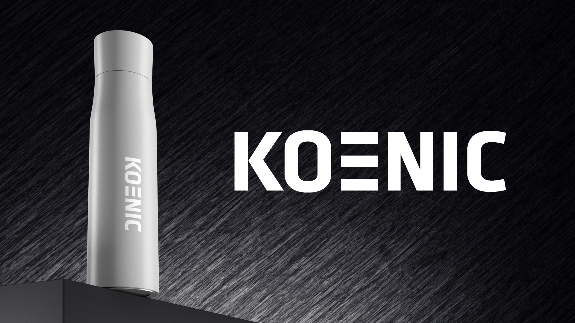 Eine weiße Flasche mit dem Text KOENIC steht auf einer schwarzen Fläche vor dunklem Hintergrund.