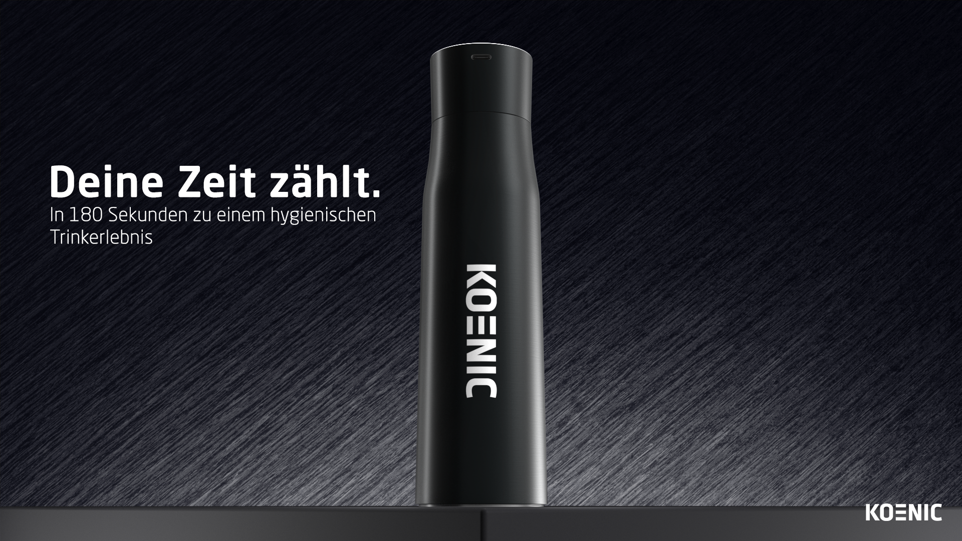 Schwarze Trinkflasche mit dem KOENIC-Logo auf dunklem Hintergrund.