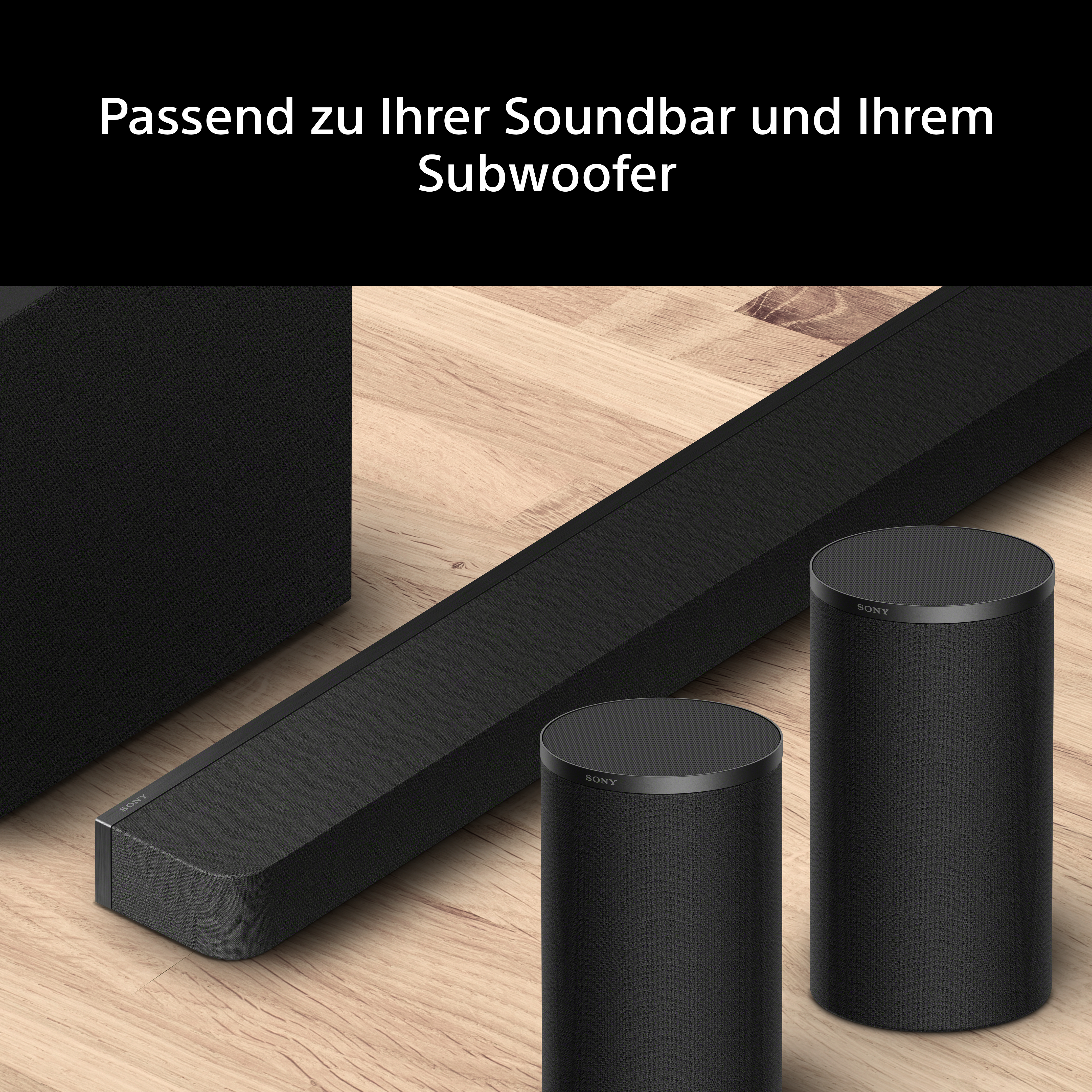 Schwarze Sony Soundbar und zwei zylindrische Lautsprecher auf hellem Holzboden.