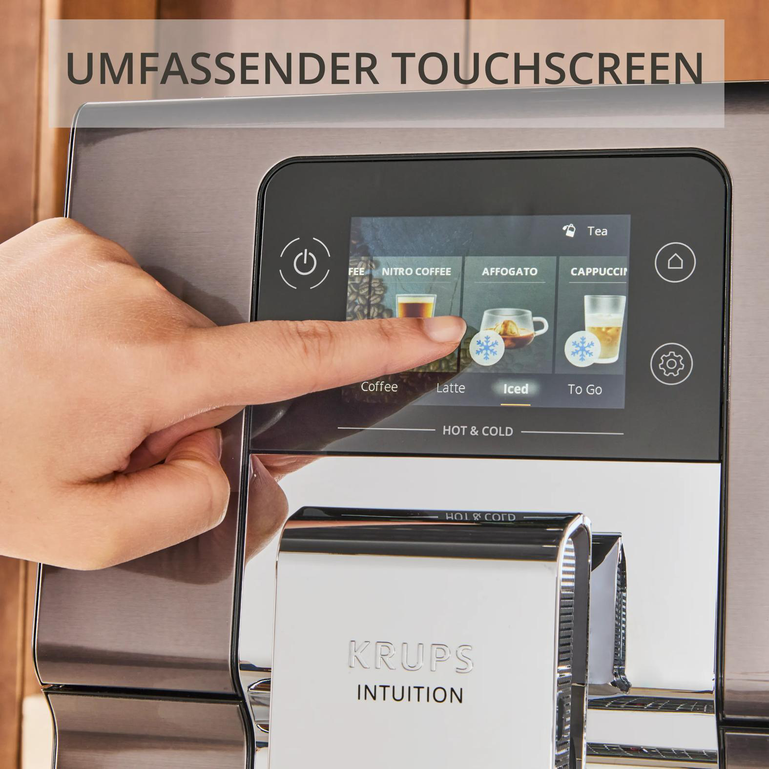 Eine Hand tippt auf den Touchscreen einer KRUPS Kaffeemaschine. Optionen: Kaffee, Latte, Iced, To Go.