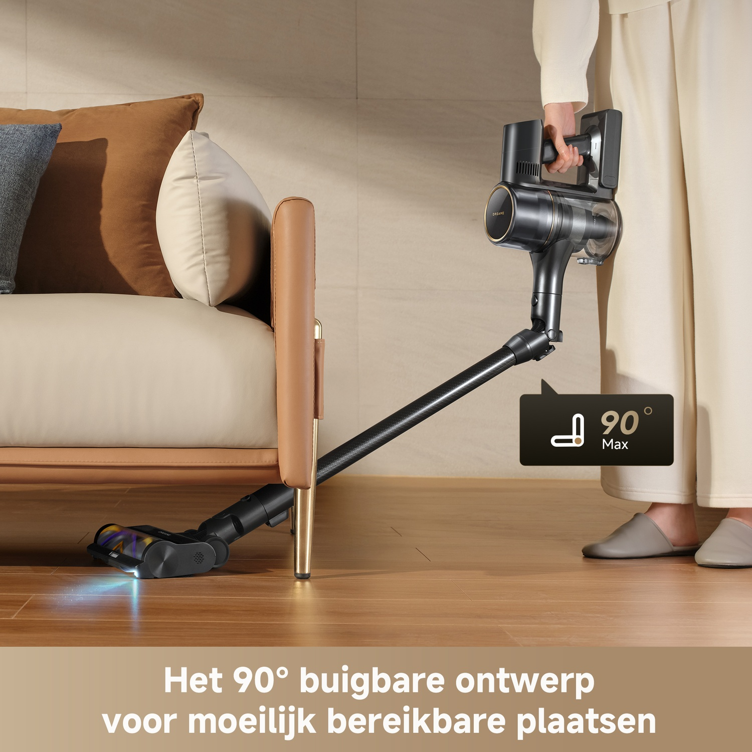 A black vacuum with a 90° bend cleans under a brown couch.