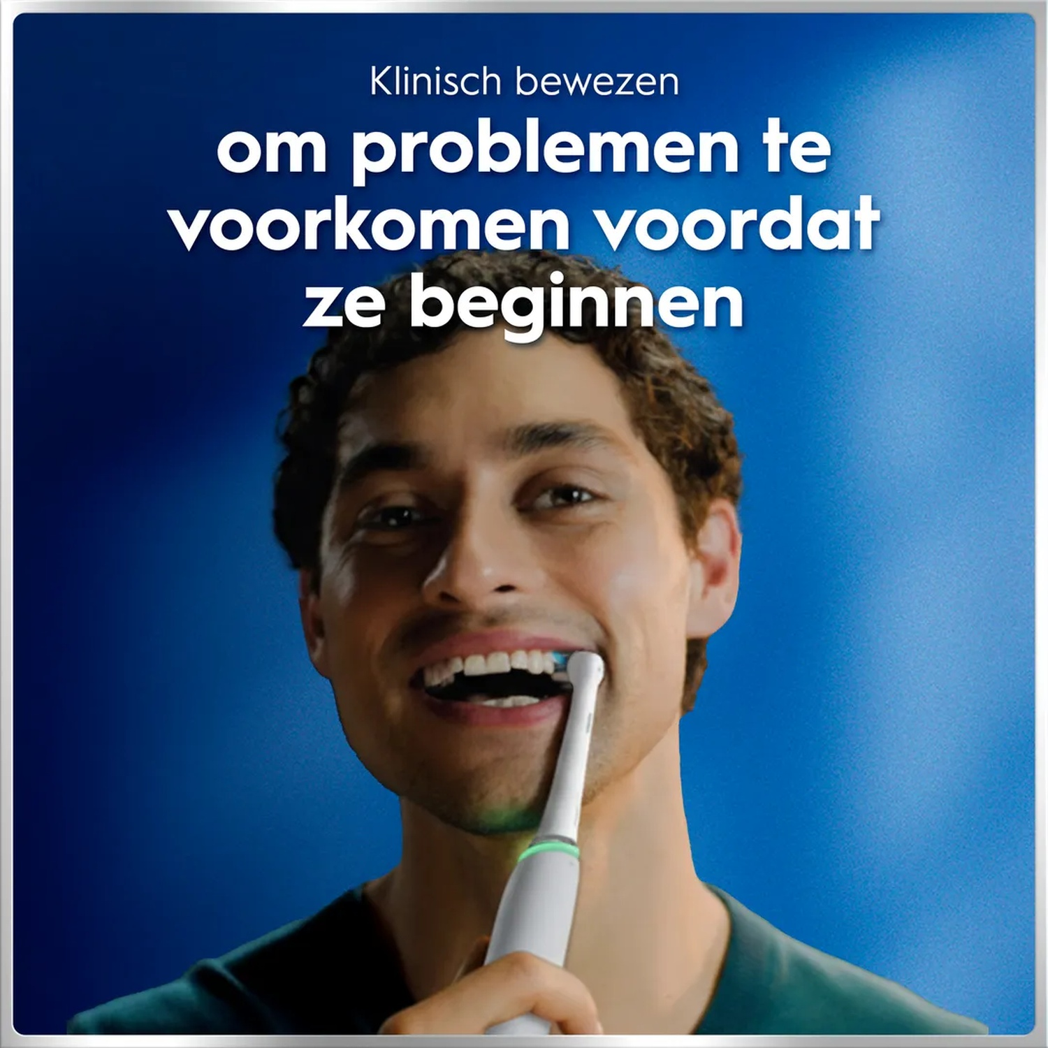 Man brushing teeth with electric toothbrush against blue background.