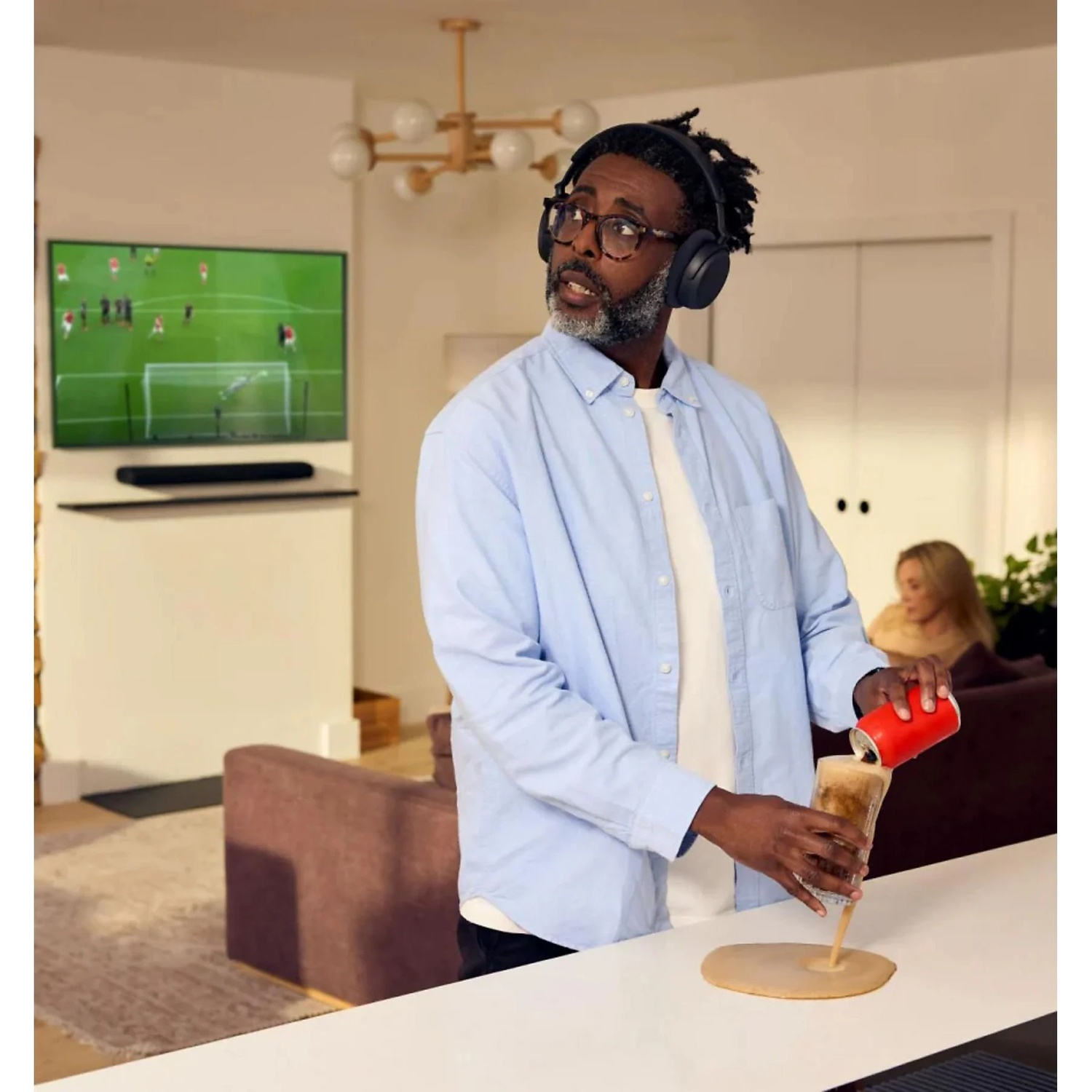 Homme avec casque renverse une boisson sur la table en regardant un match.
