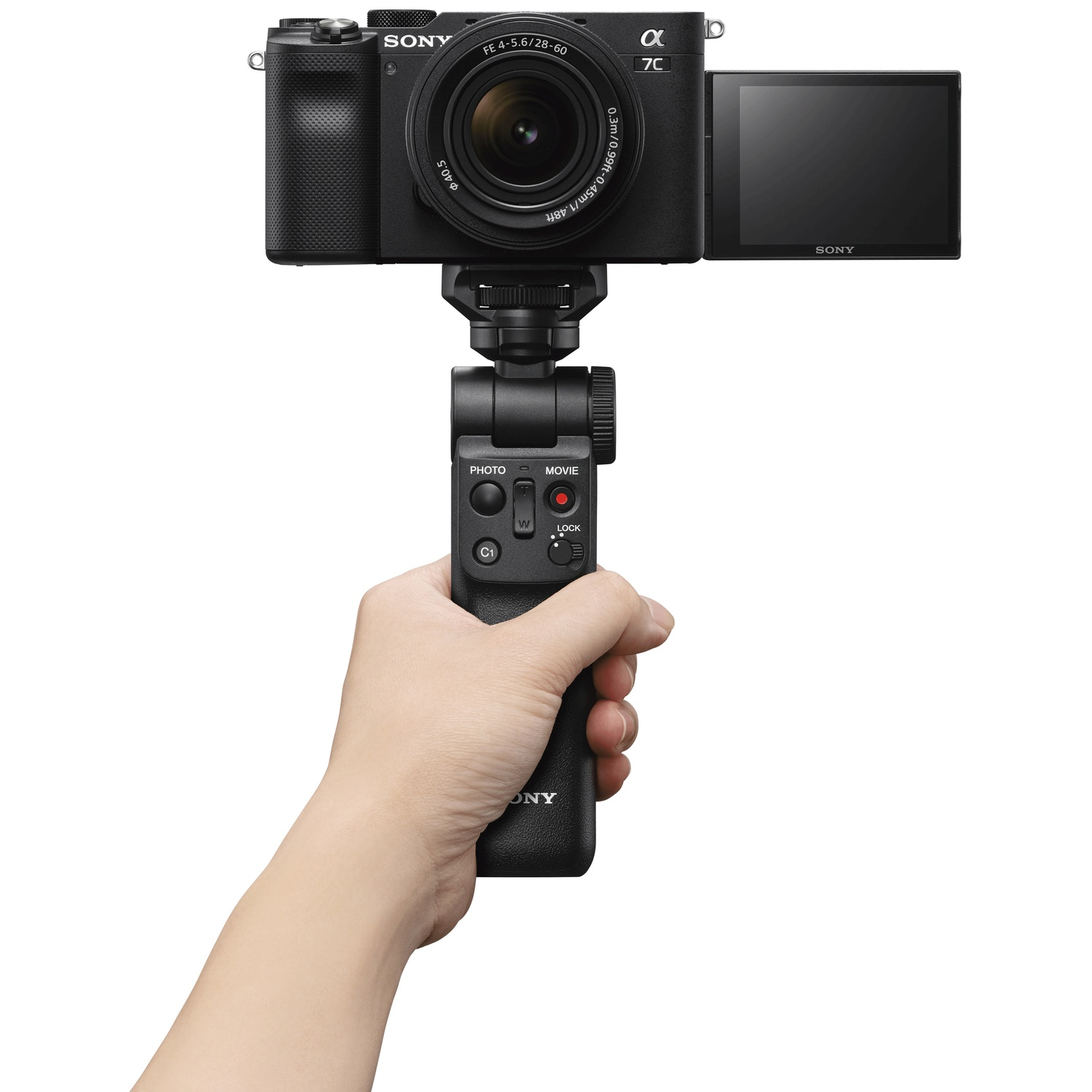 A hand holds a black Sony Alpha 7C camera set with a grip.