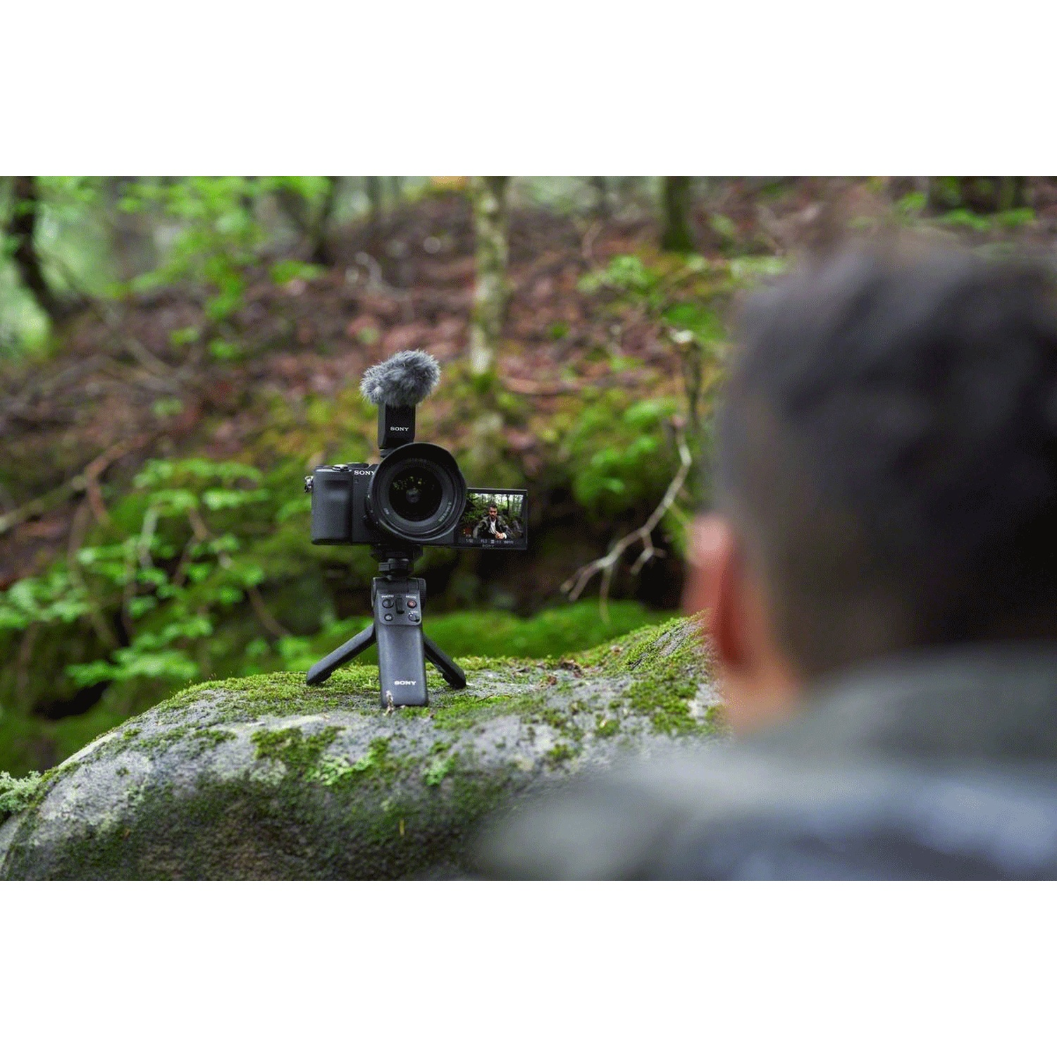 Camera with microphone on a mossy rock in a forest setting.