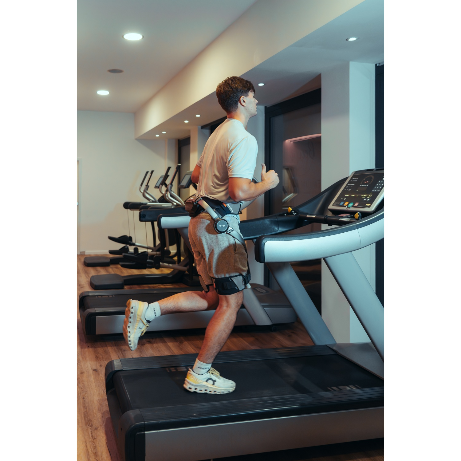 Un uomo con attrezzatura EMS corre su un tapis roulant in una palestra.