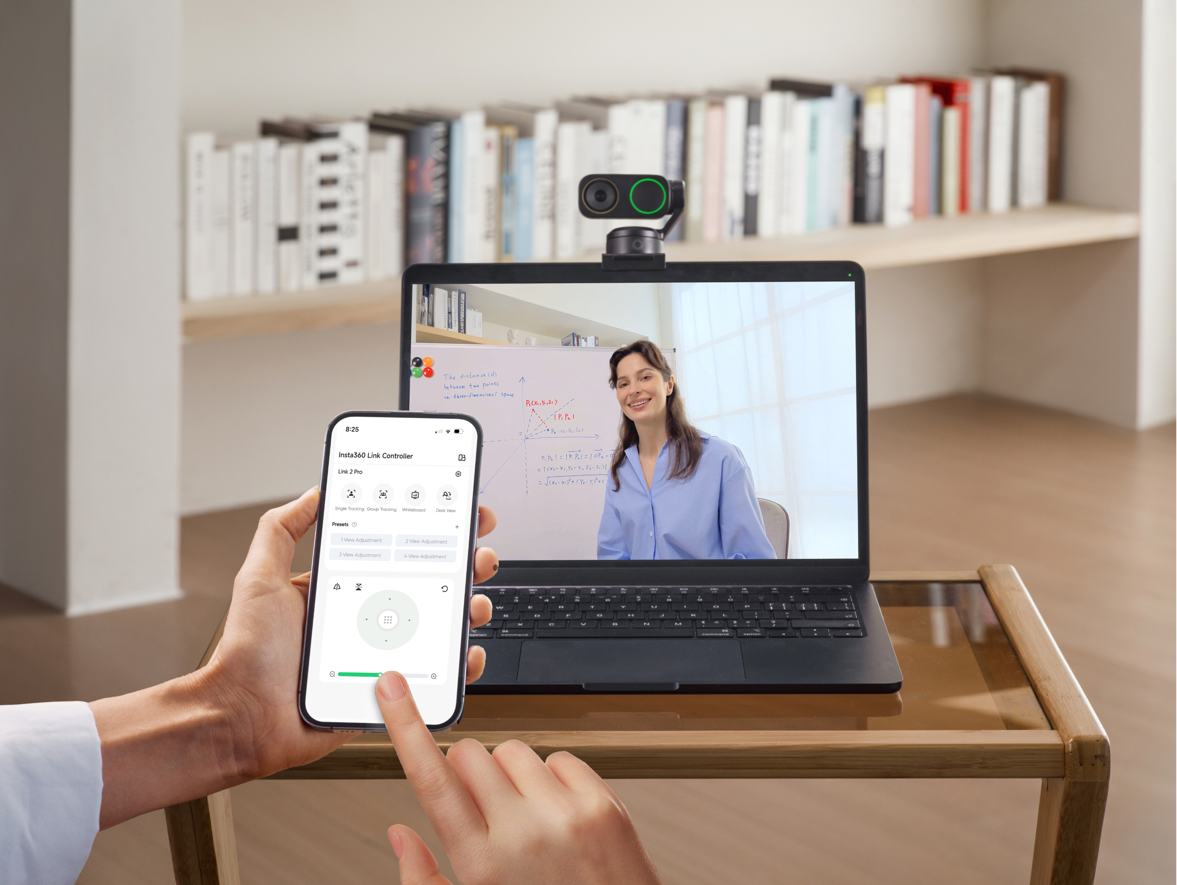 Eine Person hält ein Smartphone mit einer App, um eine Laptop-Webcam zu steuern.