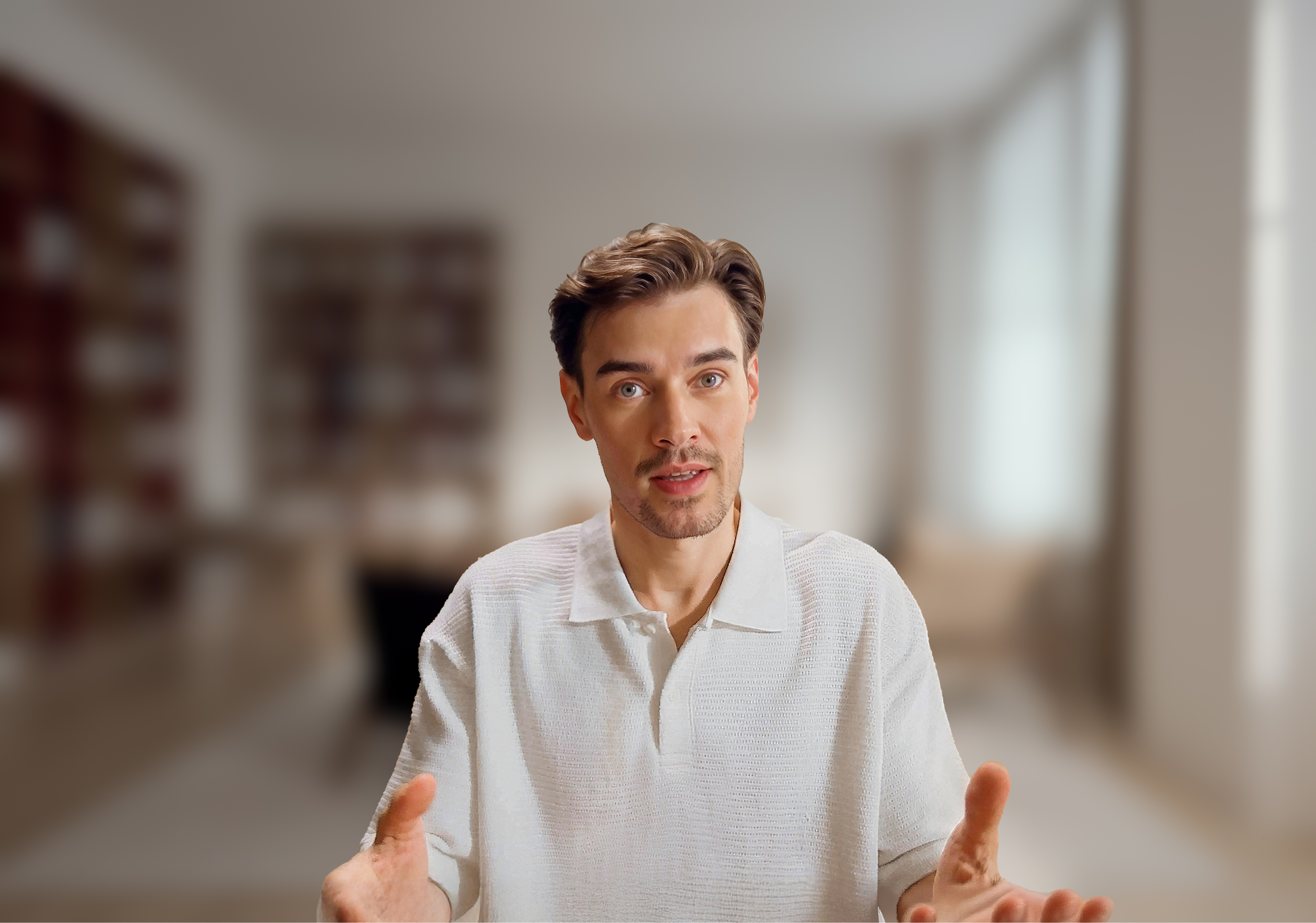 Ein Mann mit braunen Haaren in einem weißen Poloshirt gestikuliert.