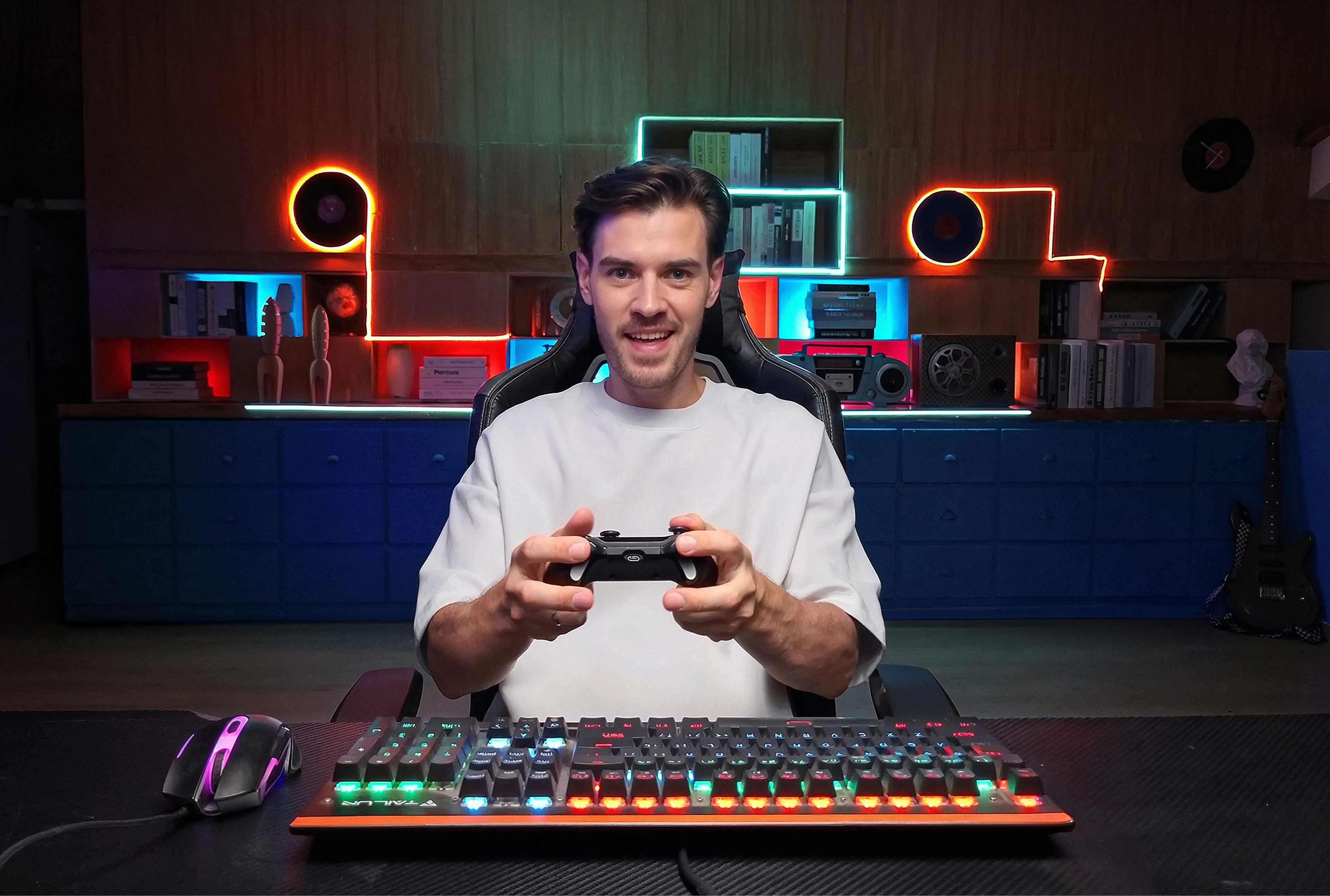 Ein Mann sitzt an einem Schreibtisch mit Tastatur und Maus und hält einen Controller.