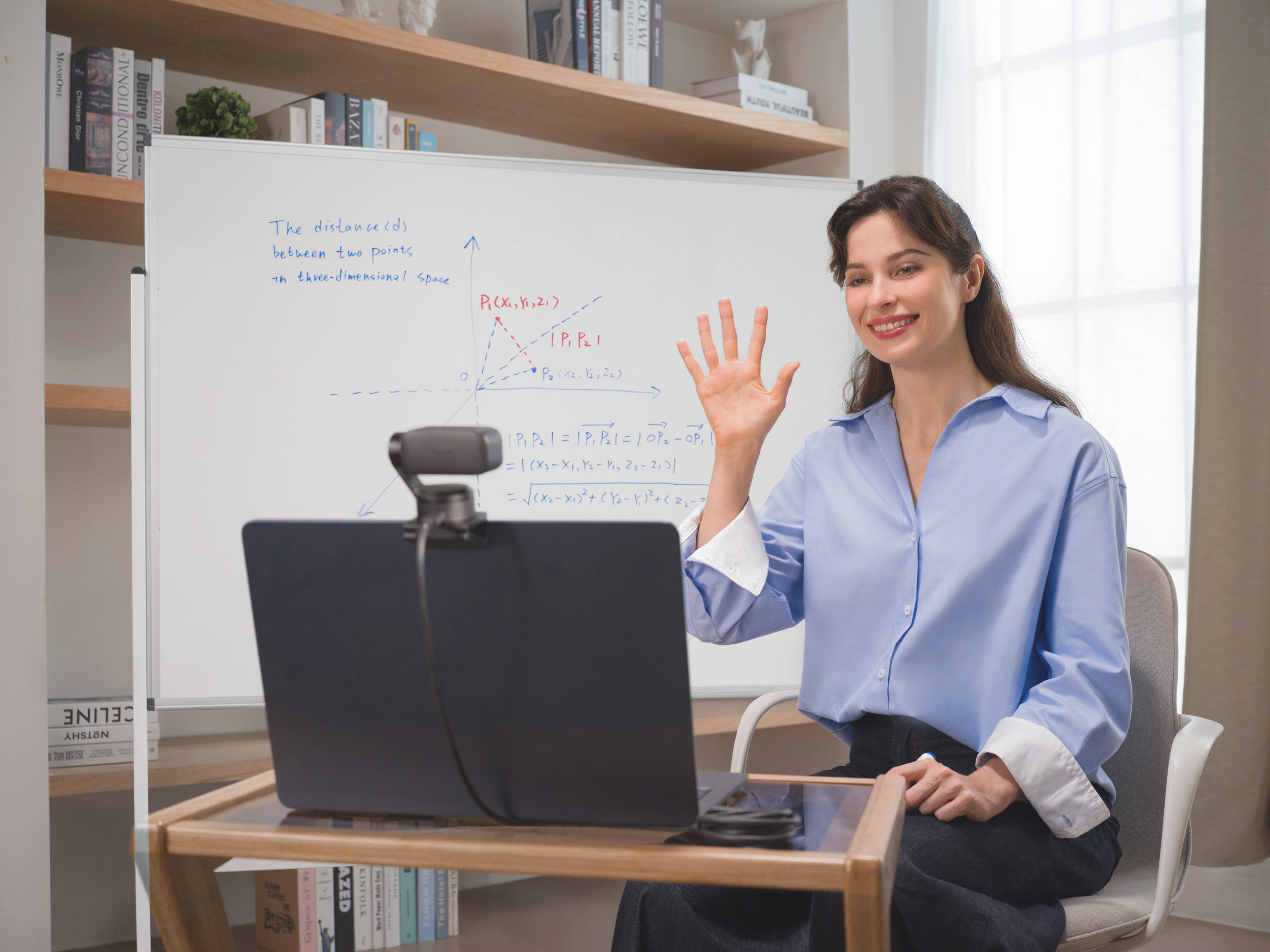 Eine Frau winkt vor einem Whiteboard mit mathematischen Formeln und einer 3D-Grafik.
