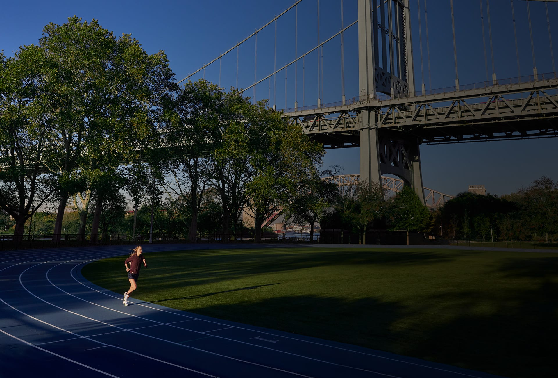 Une femme court sur une piste bleue sous un pont.
