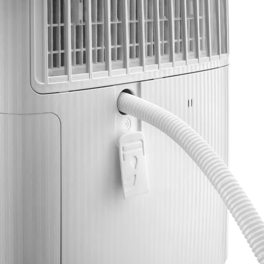 Un tuyau blanc sort d'un appareil blanc avec une grille de ventilation.