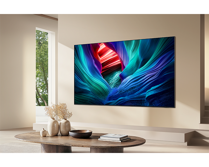 Ein großer Fernseher zeigt ein farbenfrohes, abstraktes Bild in einem modernen Wohnzimmer mit Couchtisch.