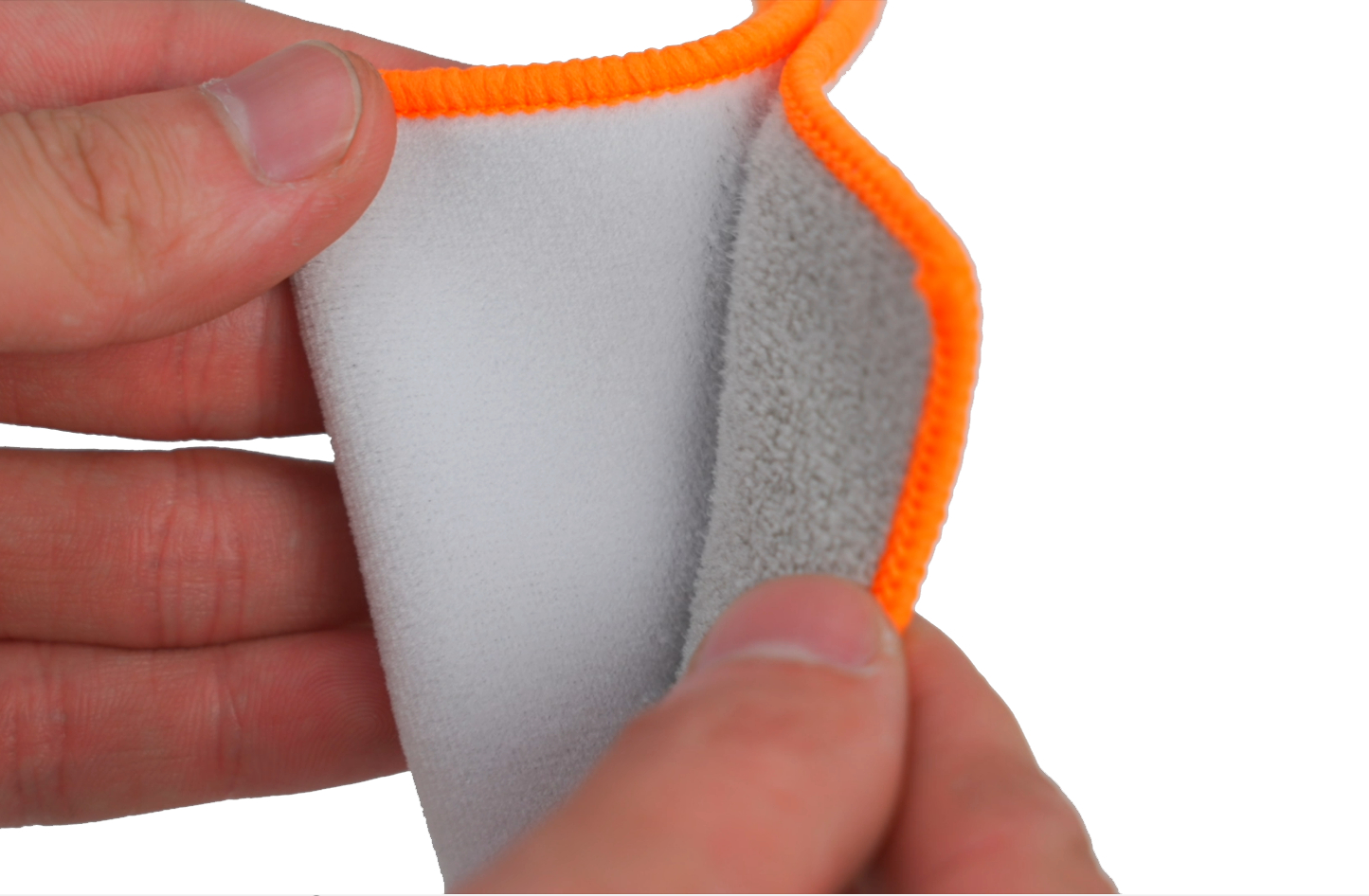 Hände falten ein weißes Mikrofasertuch mit orangem Saum.