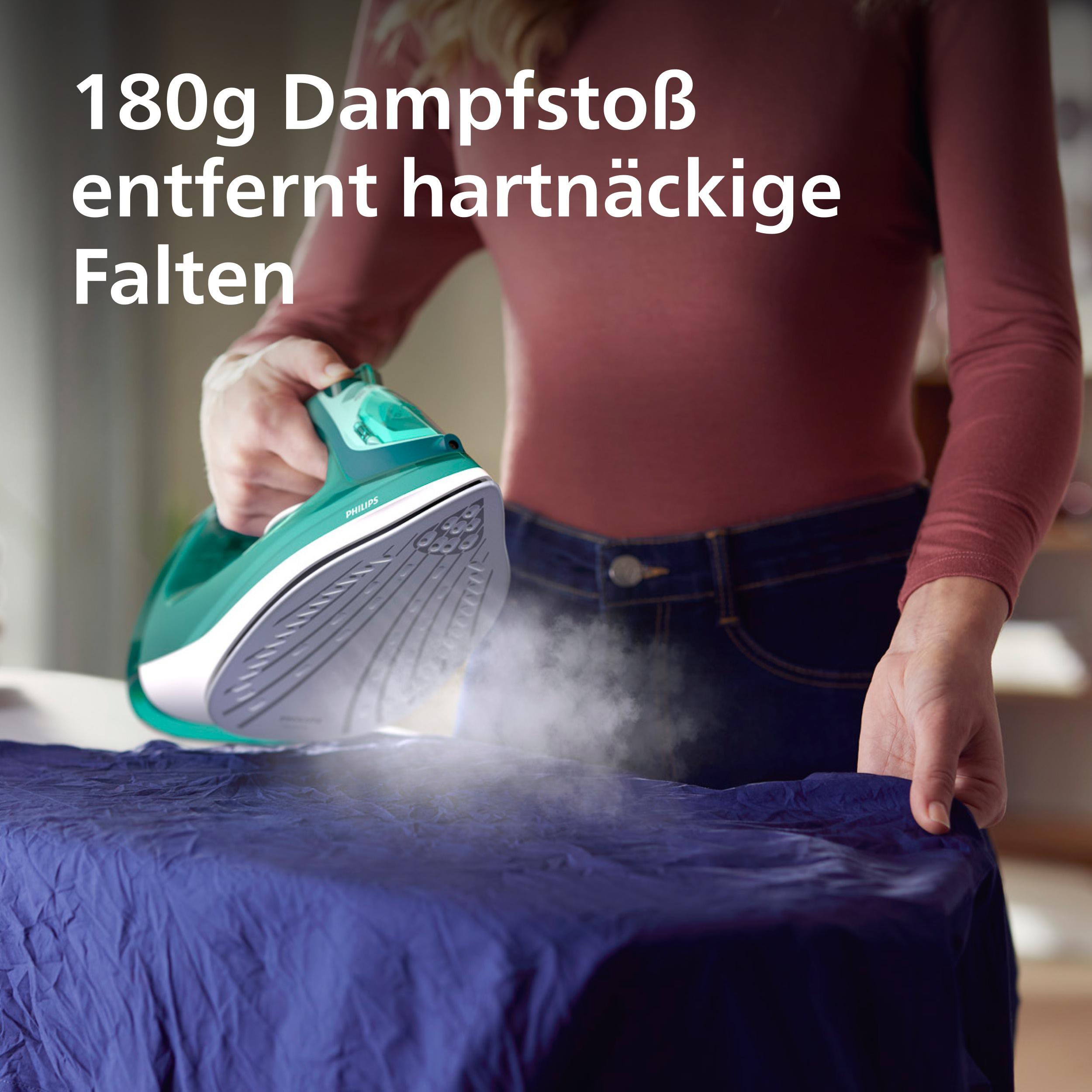 Eine grüne Dampfbügeleisen-Sohle dampft auf einem blauen Stoff.