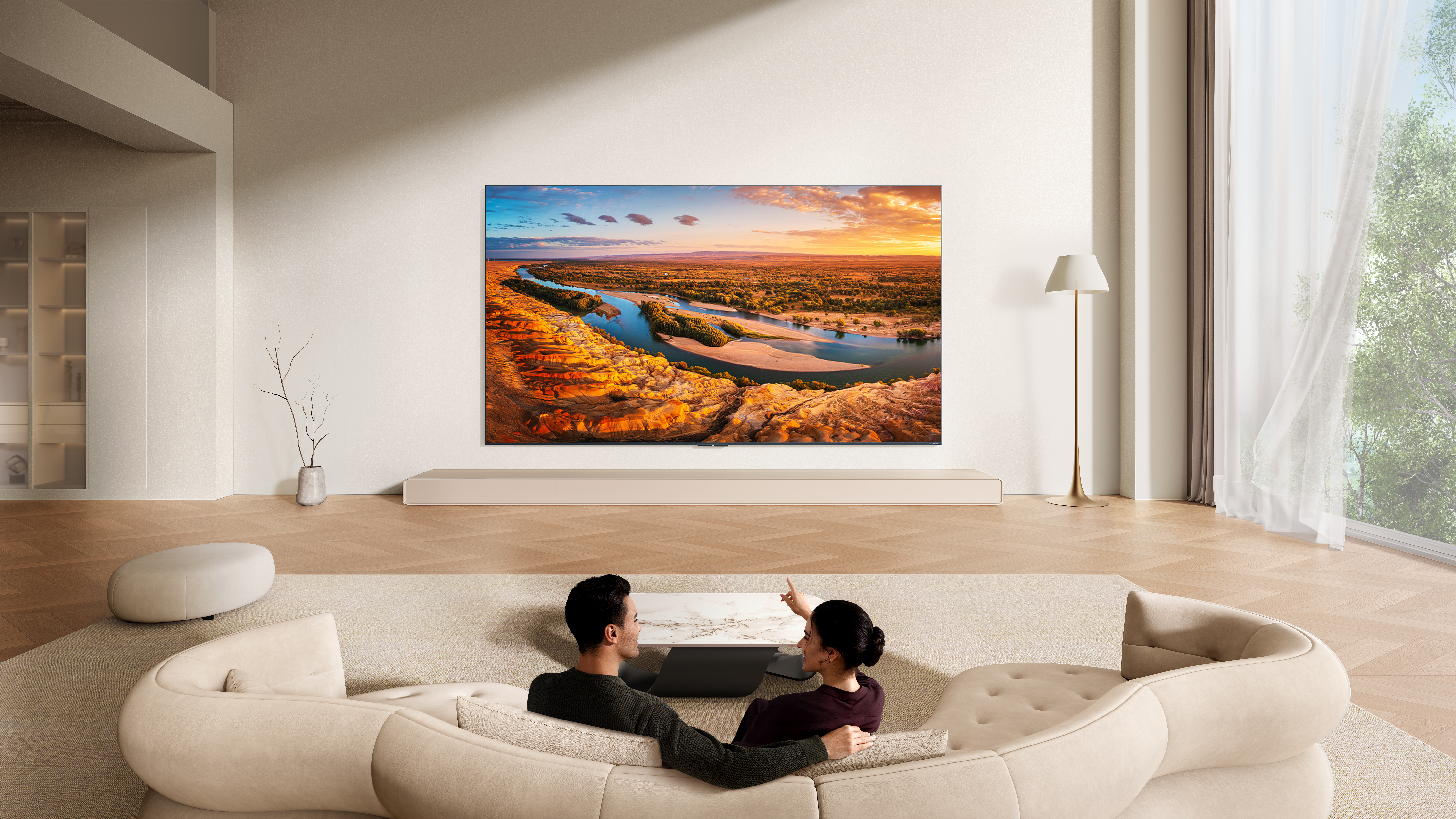 Ein Paar sitzt auf einer Couch und schaut auf einen Fernseher, der eine Wüstenlandschaft zeigt.