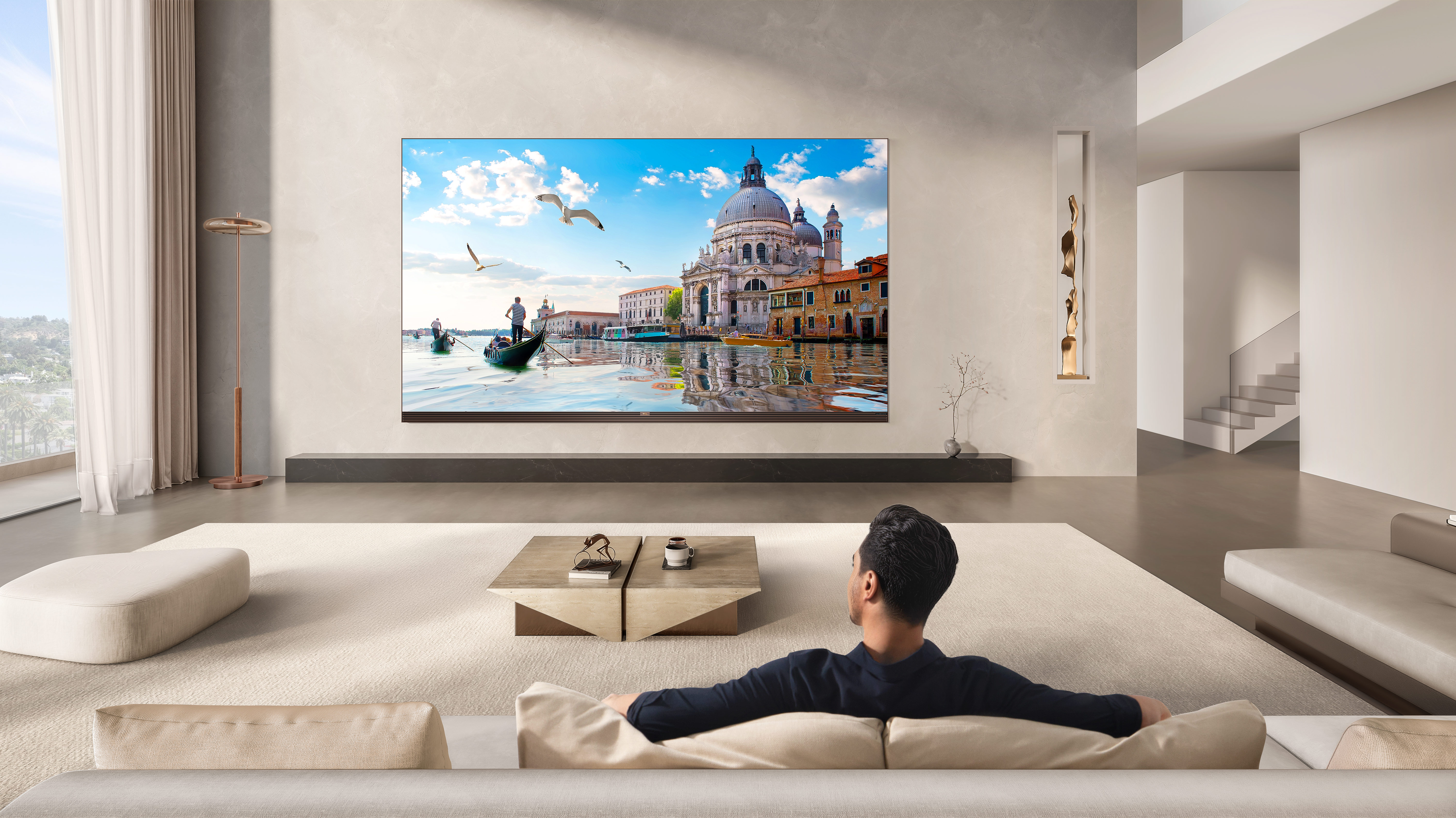 Mann sitzt auf Couch, schaut auf Venedig-Szene auf großem TV.