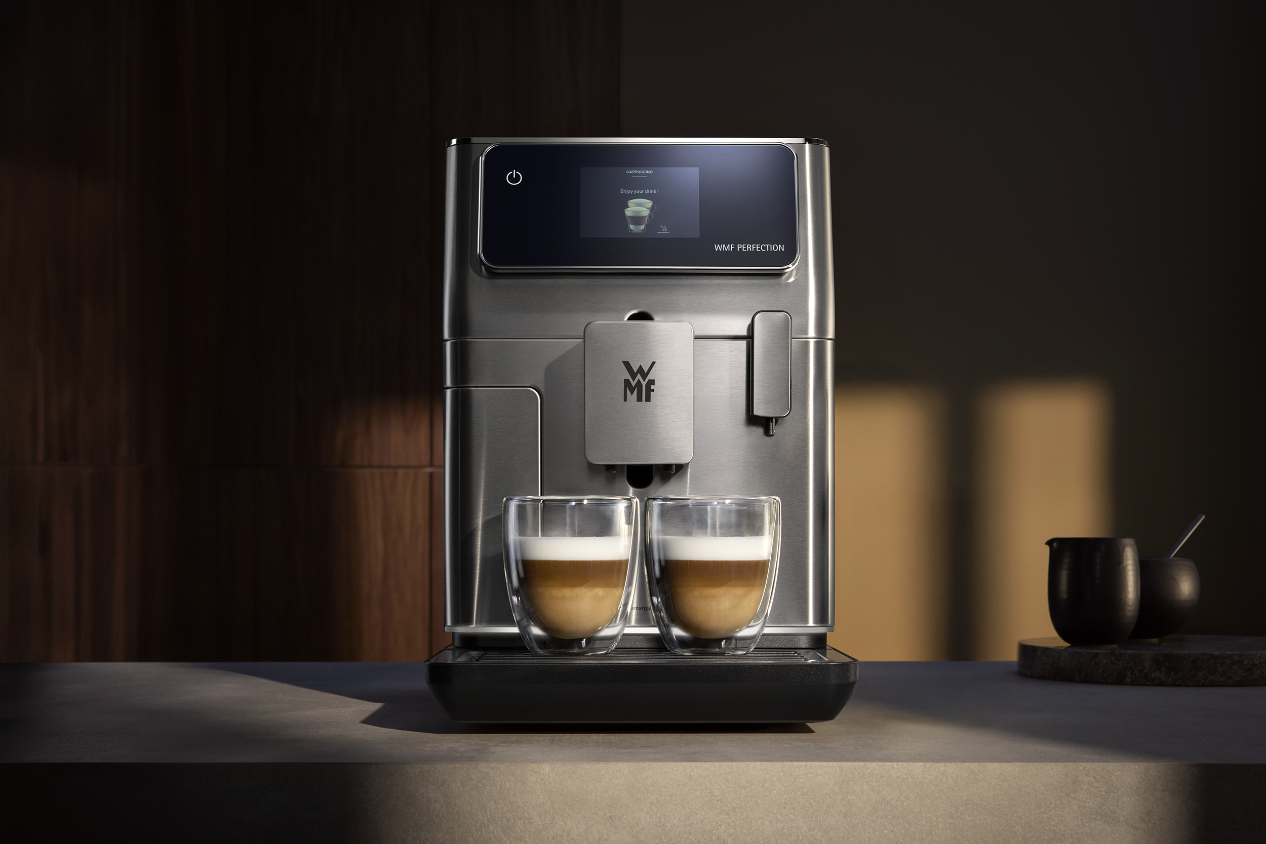 Ezüst kávéfőző két pohár cappuccinóval.