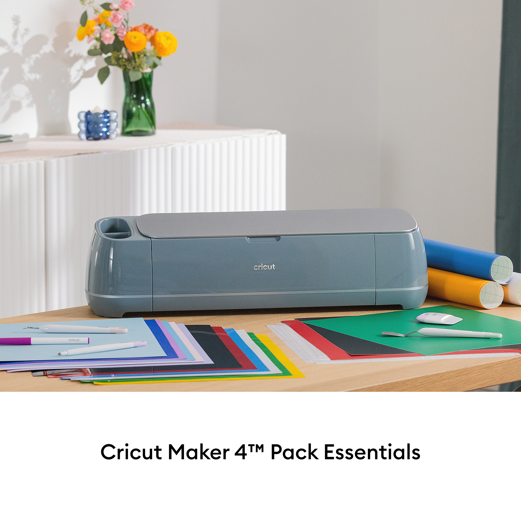 Un Cricut Maker 4 azul con materiales de manualidades como rollos de vinilo y papel.