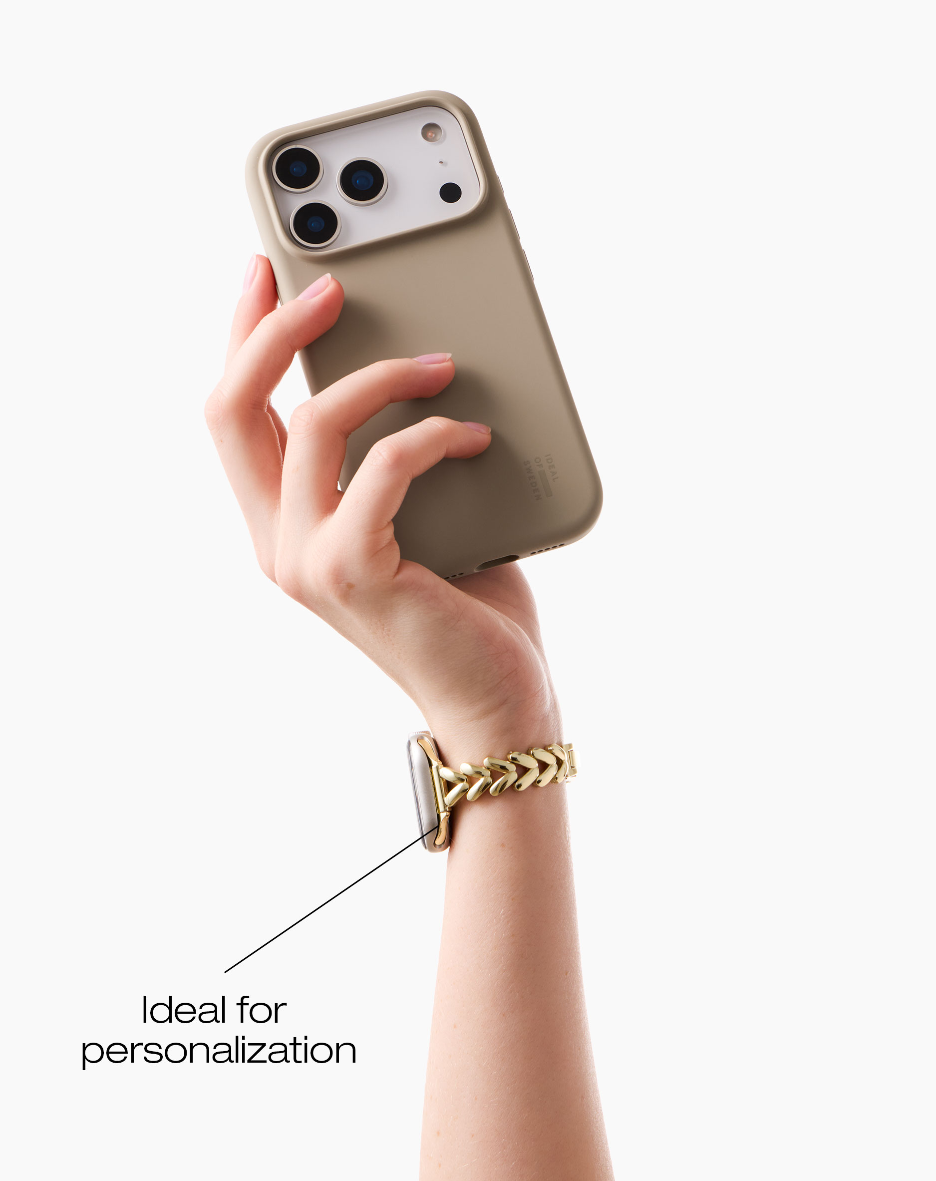 Eine Hand hält ein Handy mit beige Hülle. Eine goldene Uhr ist am Armgelenk.