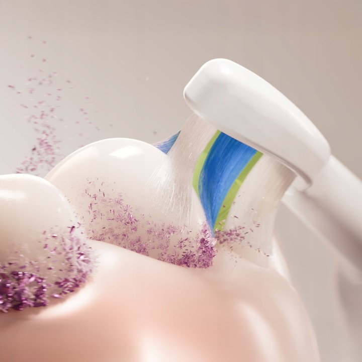 Szczoteczka elektryczna czyści zęby fioletowymi drobinkami.