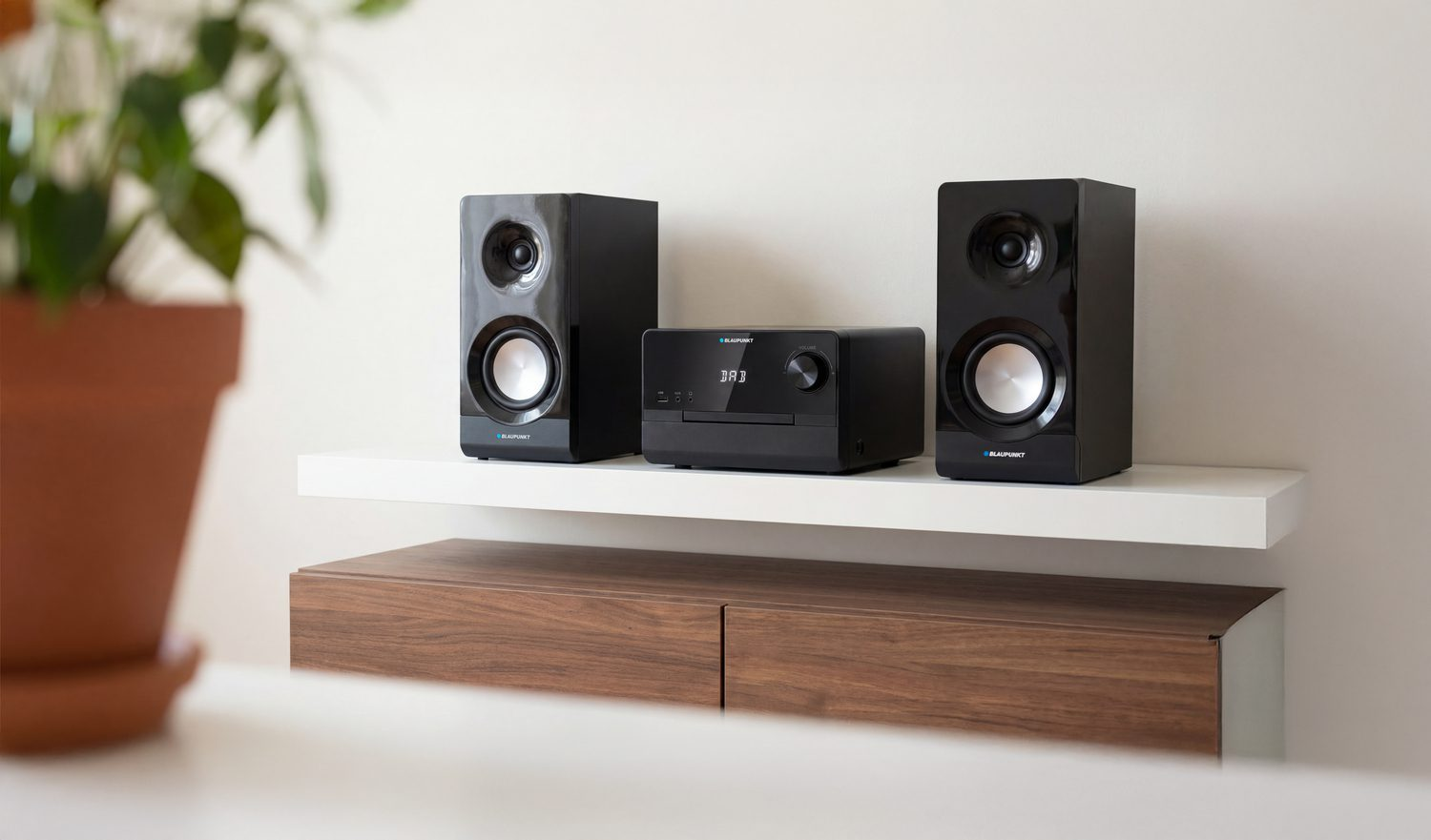 Dwa czarne głośniki i system stereo na półce.