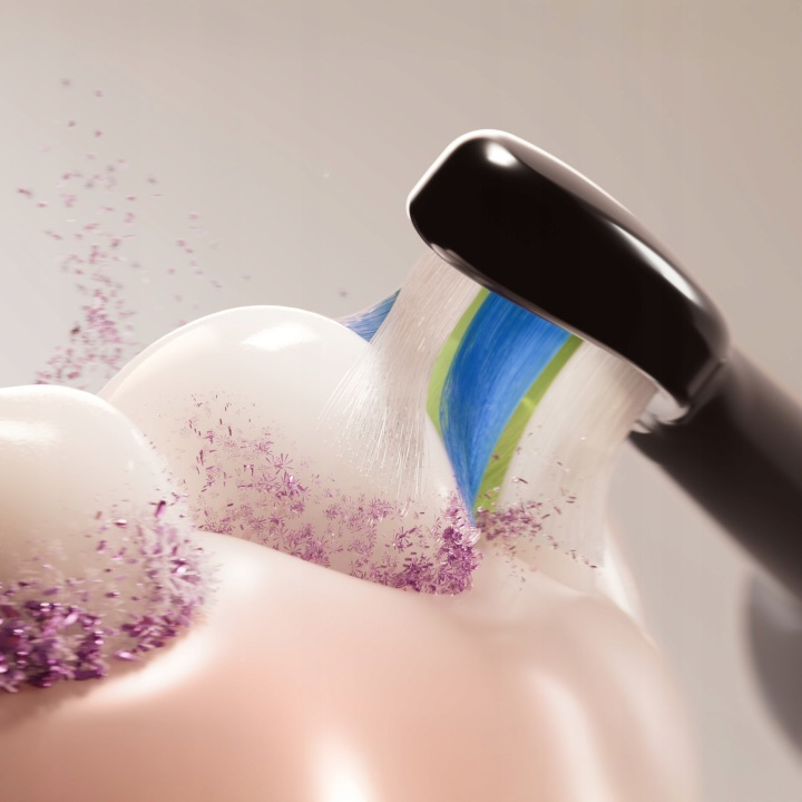 Szczoteczka elektryczna czyści zęby fioletowymi drobinkami i pianą.