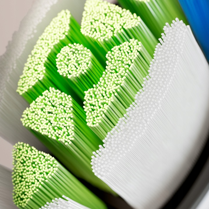 Zbliżenie włosia szczoteczki do zębów, z zielonym i białym włosiem.