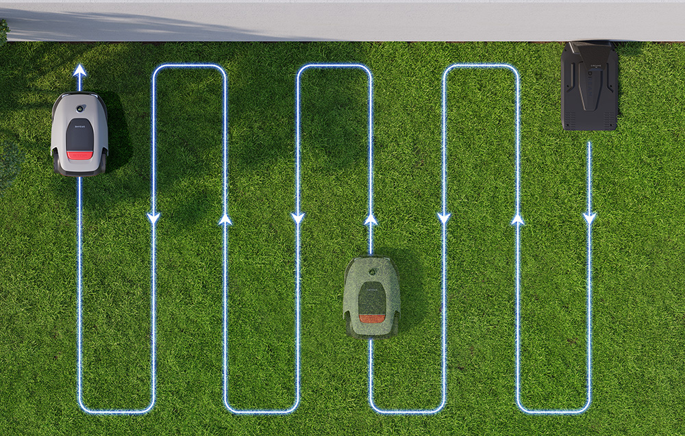 Trzy roboty koszące na trawniku z niebieskimi ścieżkami i strzałkami.