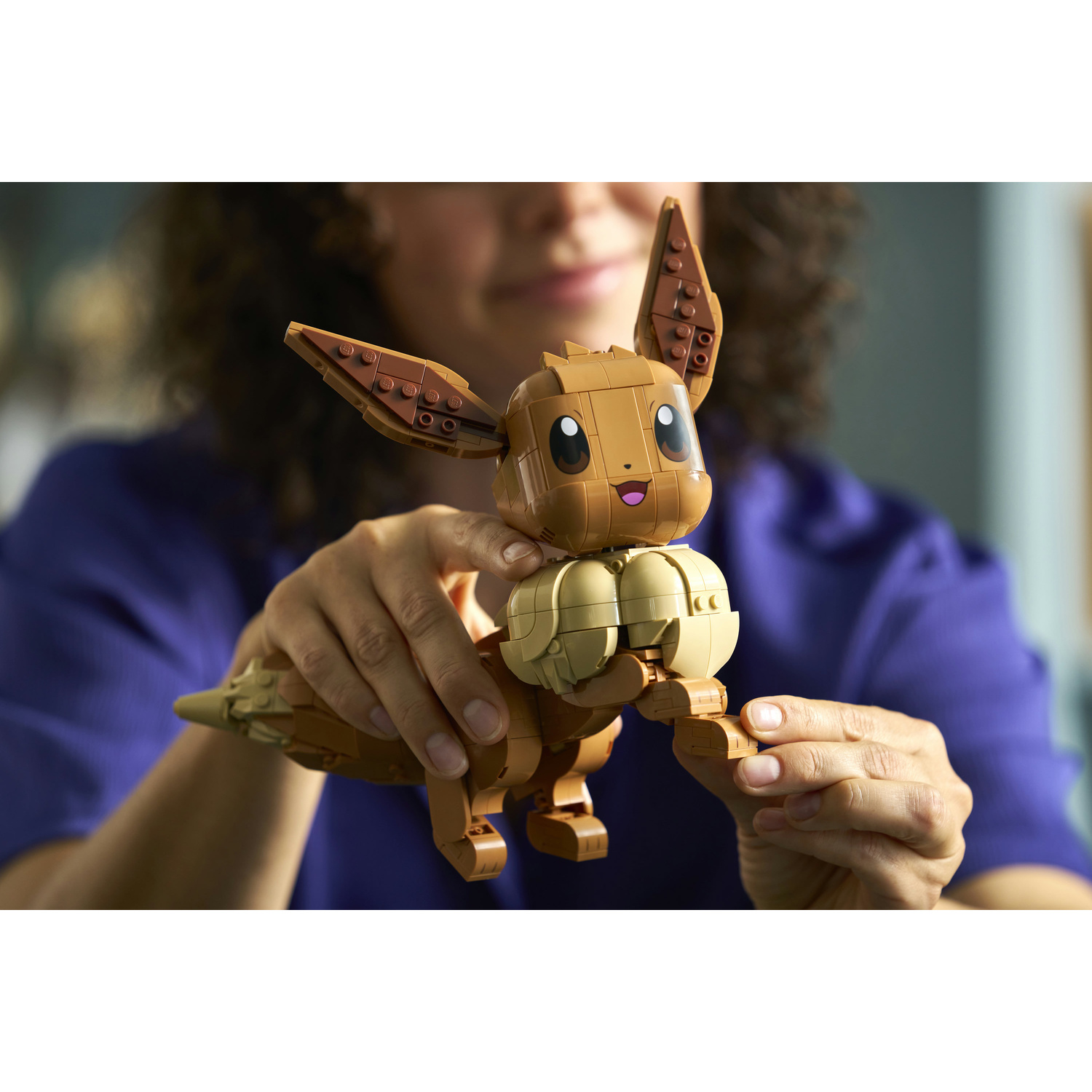 Una persona tiene una figura Lego marrone di Eevee con le orecchie alzate.
