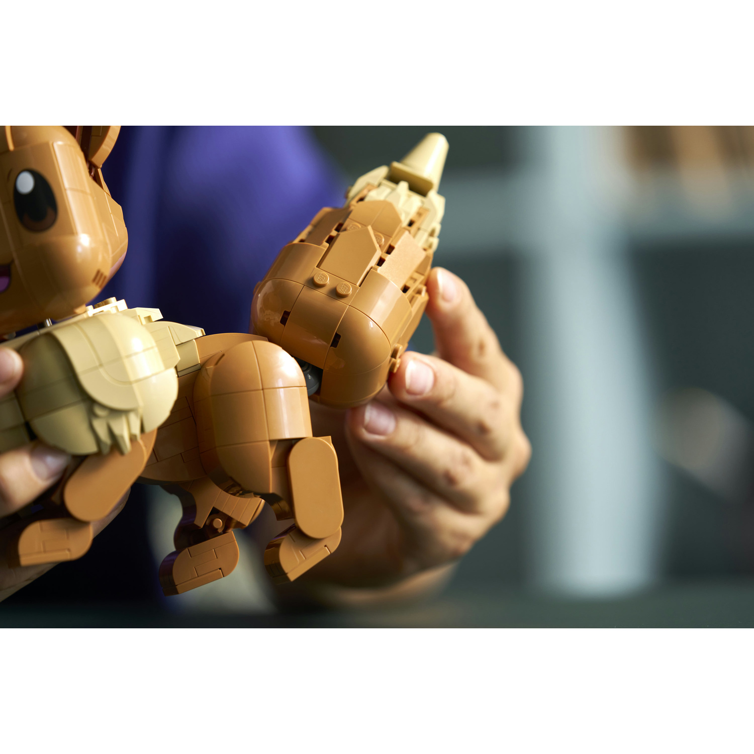 Una figura Lego marrone con grandi orecchie e coda è tenuta dalle mani.