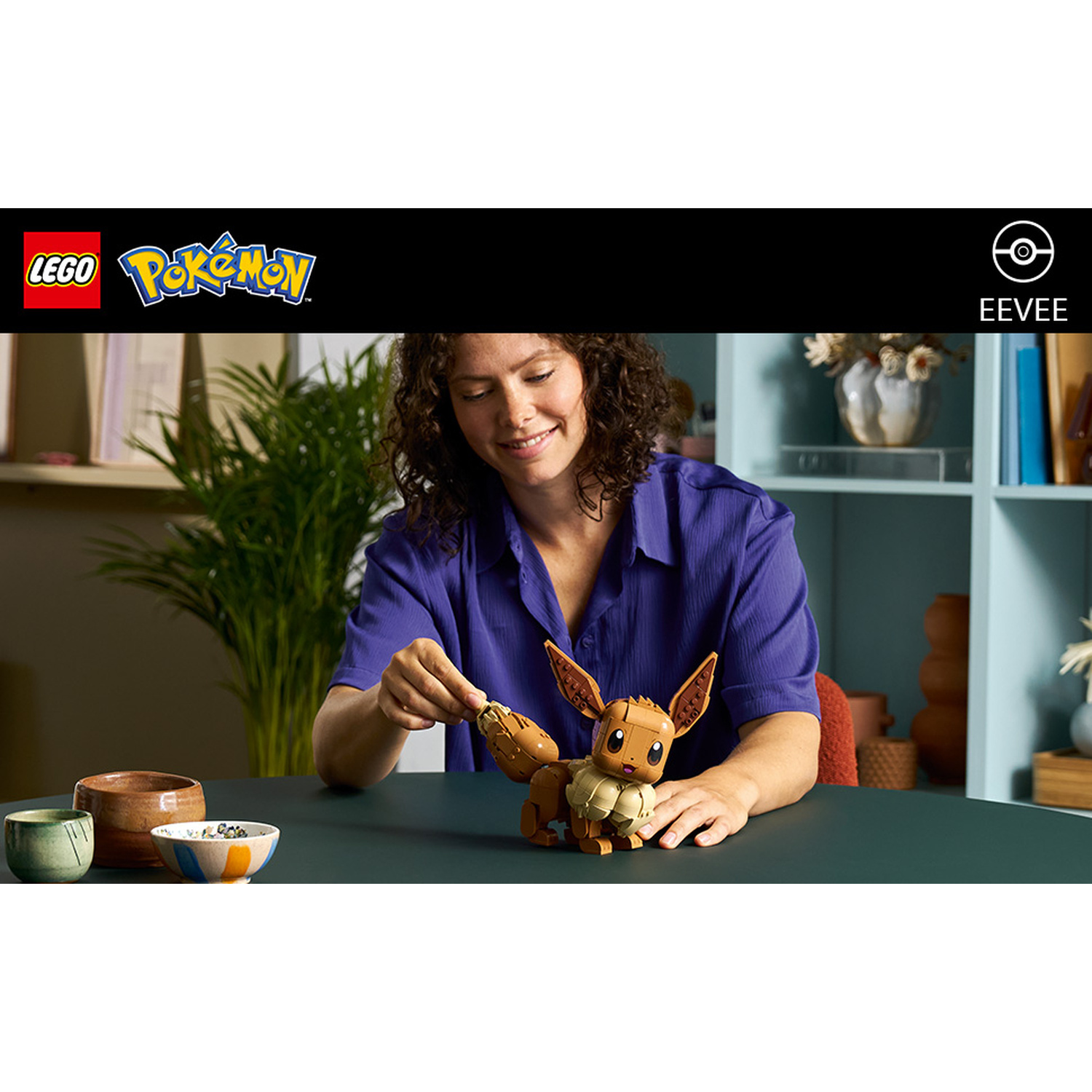 Donna costruisce Eevee Lego al tavolo con tre ciotole.