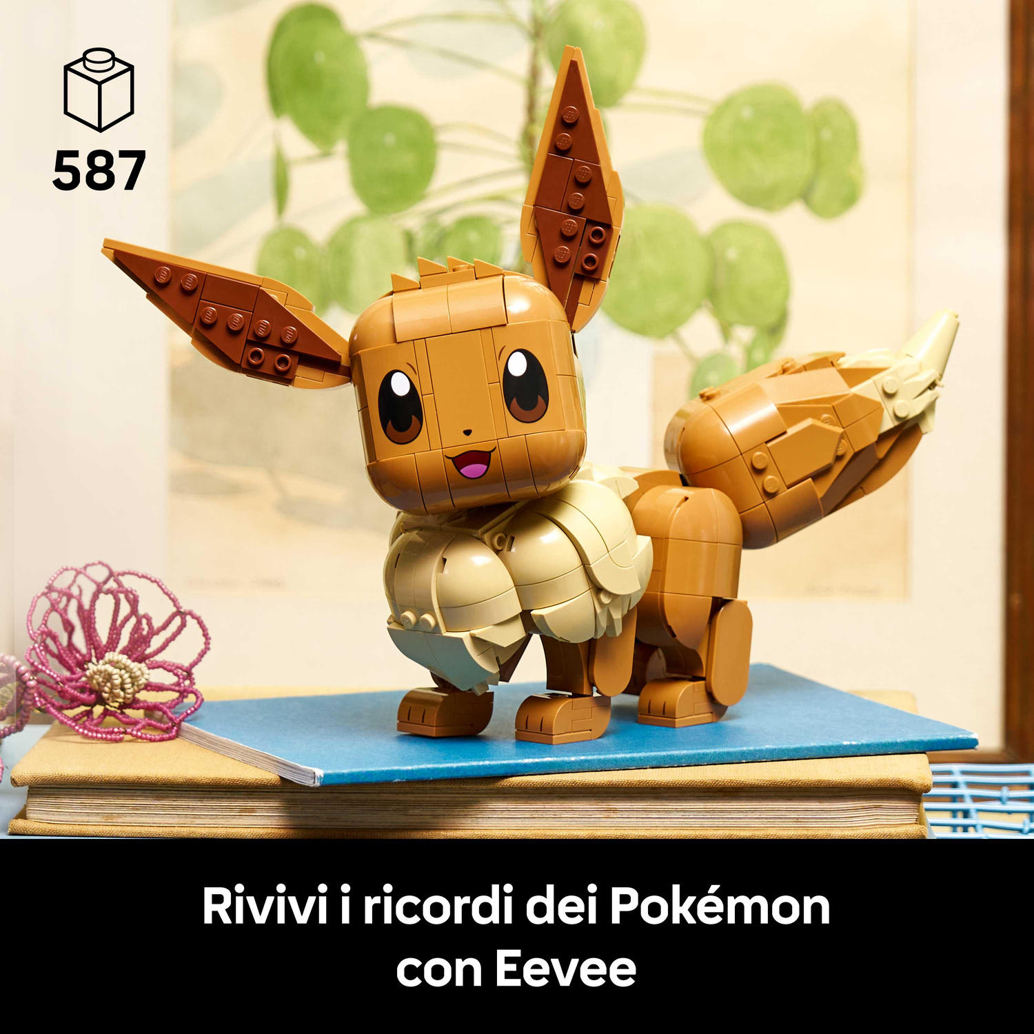 Un Eevee Lego marrone si trova su un libro blu con un fiore viola accanto.