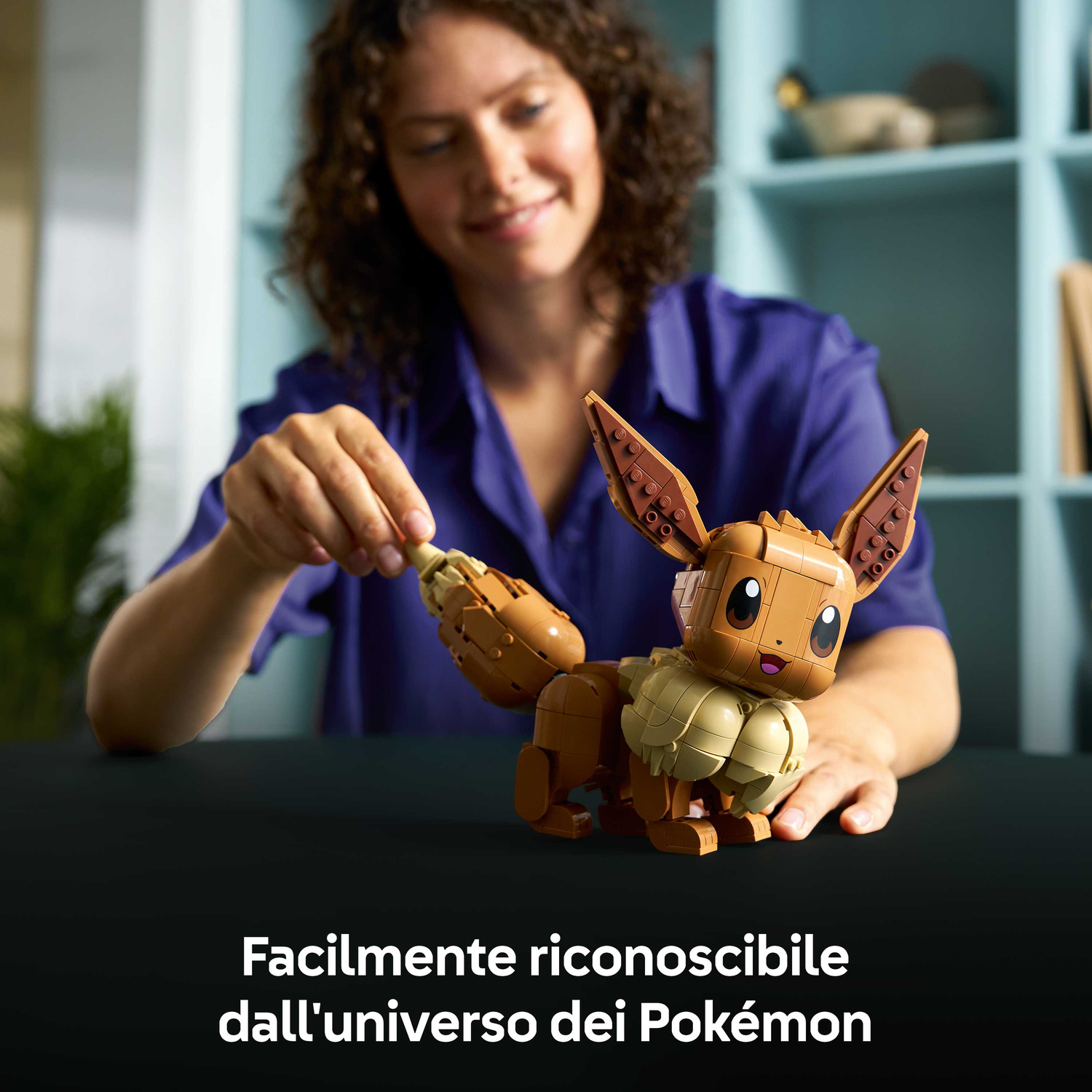 Una donna costruisce un Eevee Lego marrone, un Pokémon, a un tavolo.