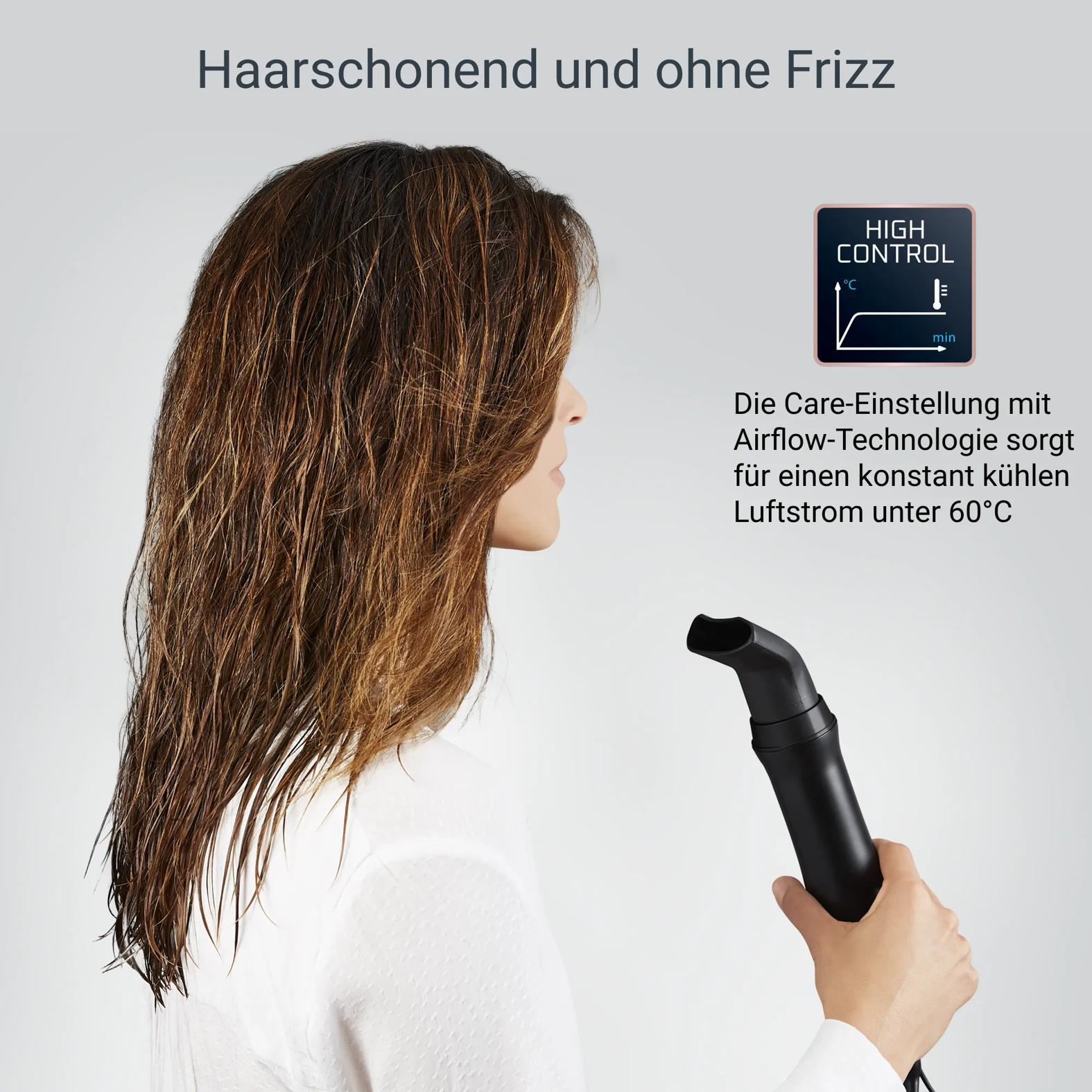 Frau mit langen Haaren, die auf einen schwarzen Haartrockneraufsatz blickt.